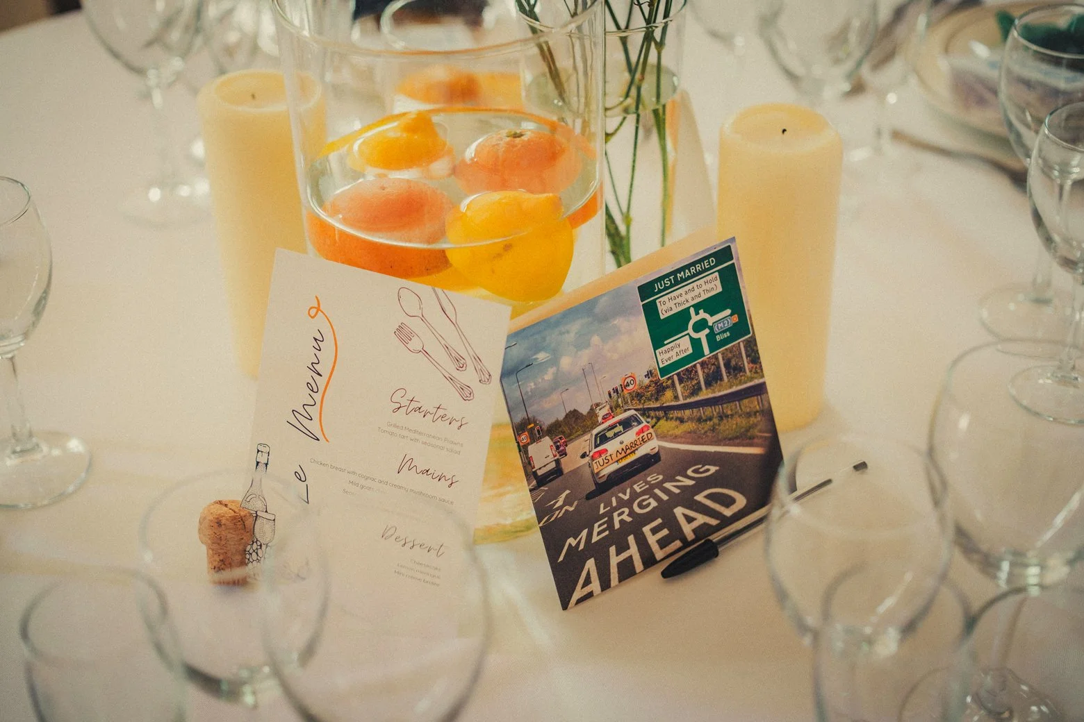 dinner table at the wedding decorated with candles, oranges, and postcard