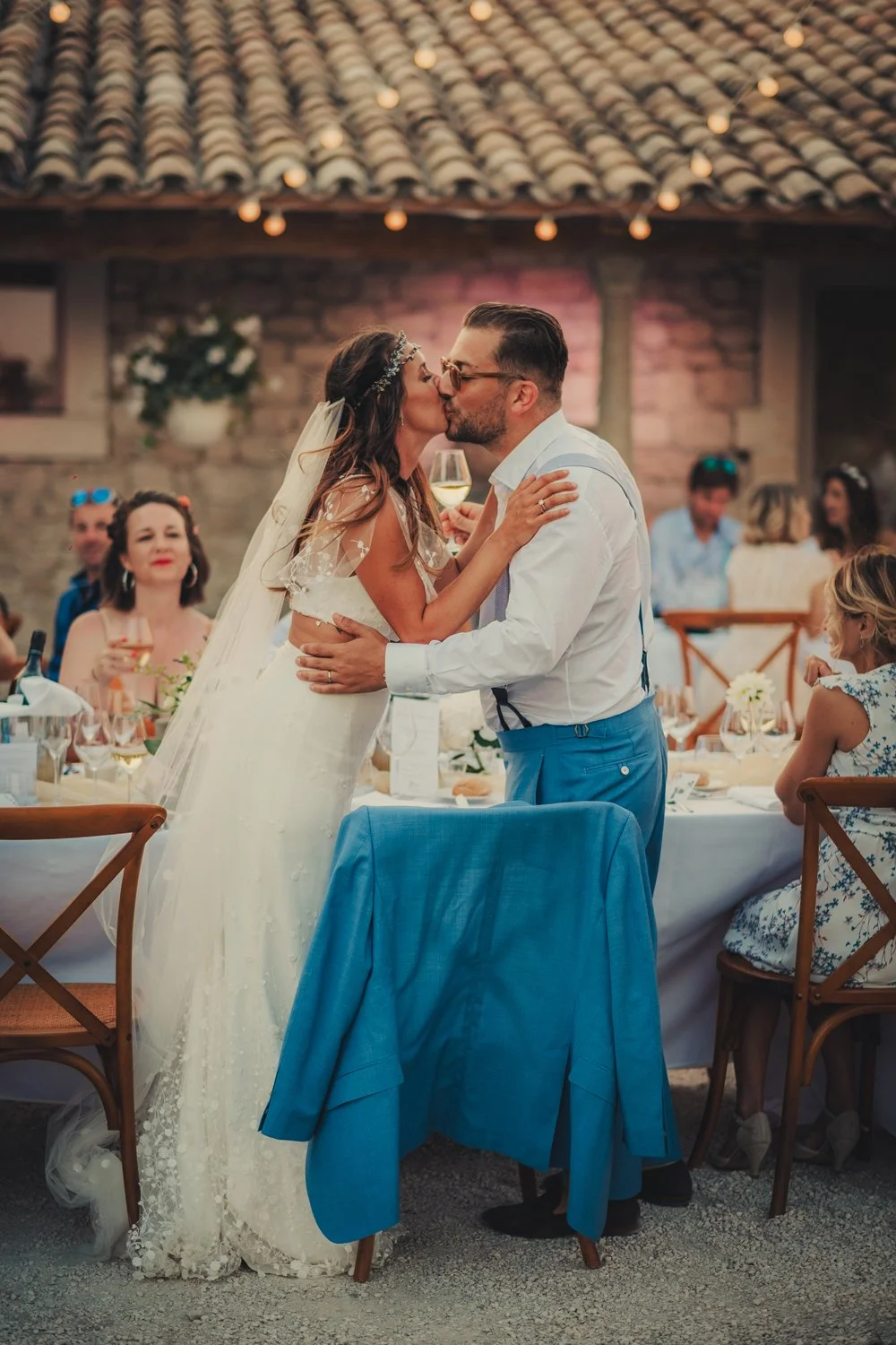 les mariés s’embrassant sous les guirlandes lumineuses pendant le dîner au Domaine de Sarson