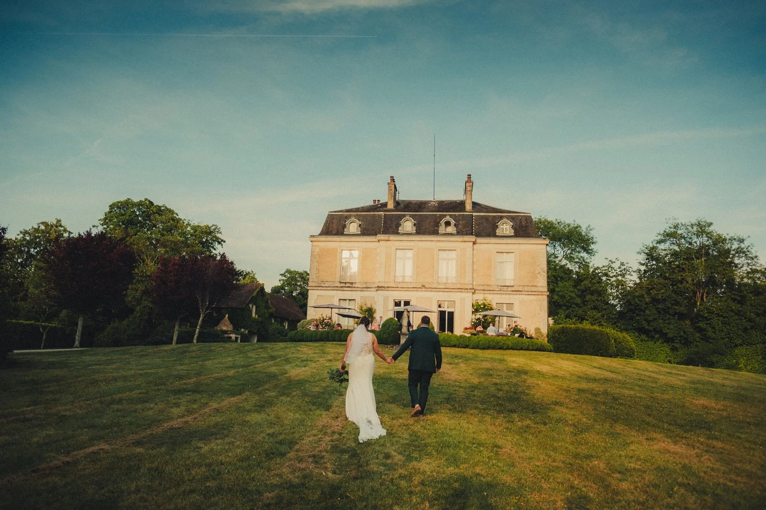 Bride and groom walking through château gardens