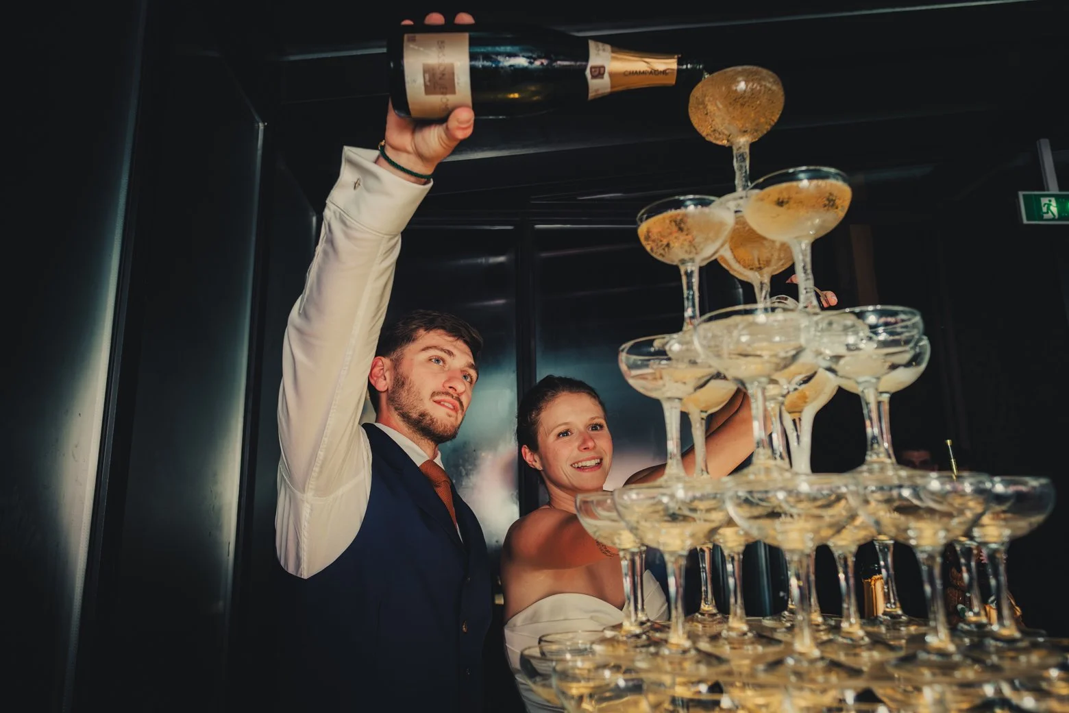 Mariés versant du champagne dans une tour de coupes lors de la réception