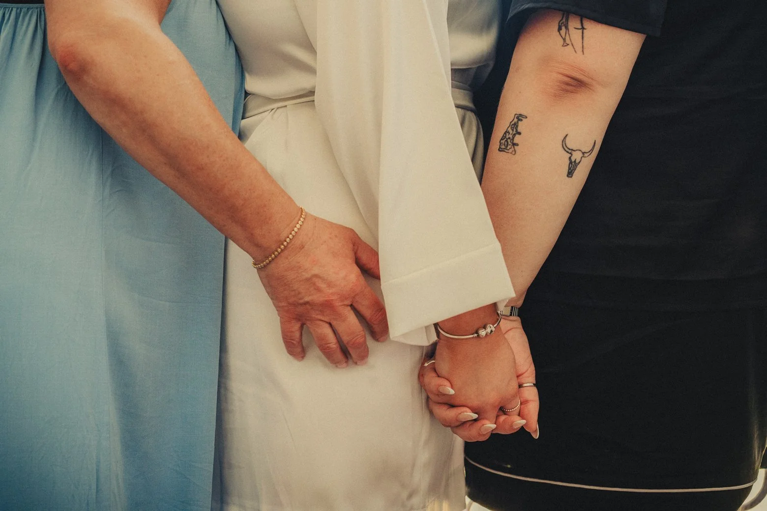 Bride holding hands with her mother and sister during wedding preparations