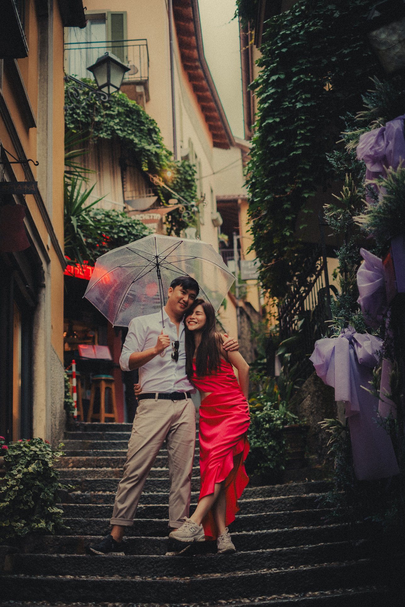 Couple posing on the stairs under an umbrella in Bellagio, Lake Como for their engagement photo session.