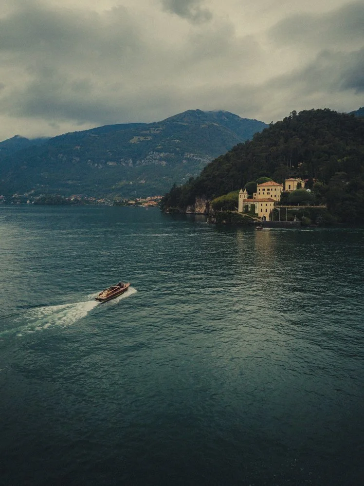Lake Como photographer capturing a classic wooden boat cruising in front of Villa del Balbianello.