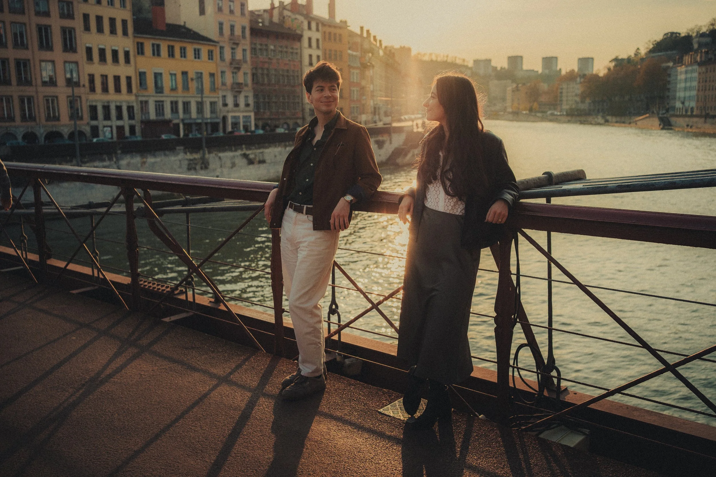 Couple pose moderne sur un pont à Lyon lumière dorée.