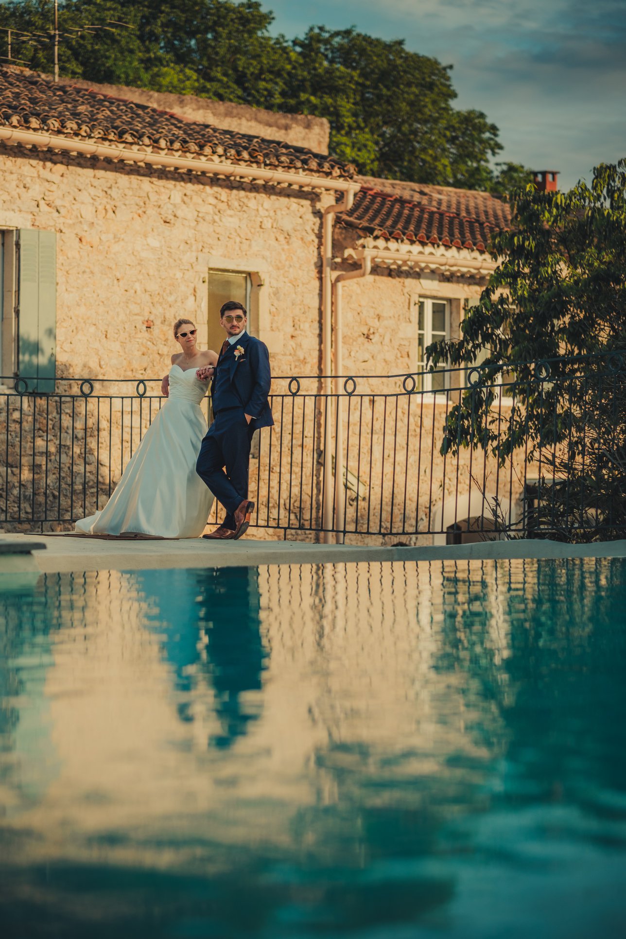 Couple de mariés posant de façon décontractée près de la piscine du Domaine des Rives