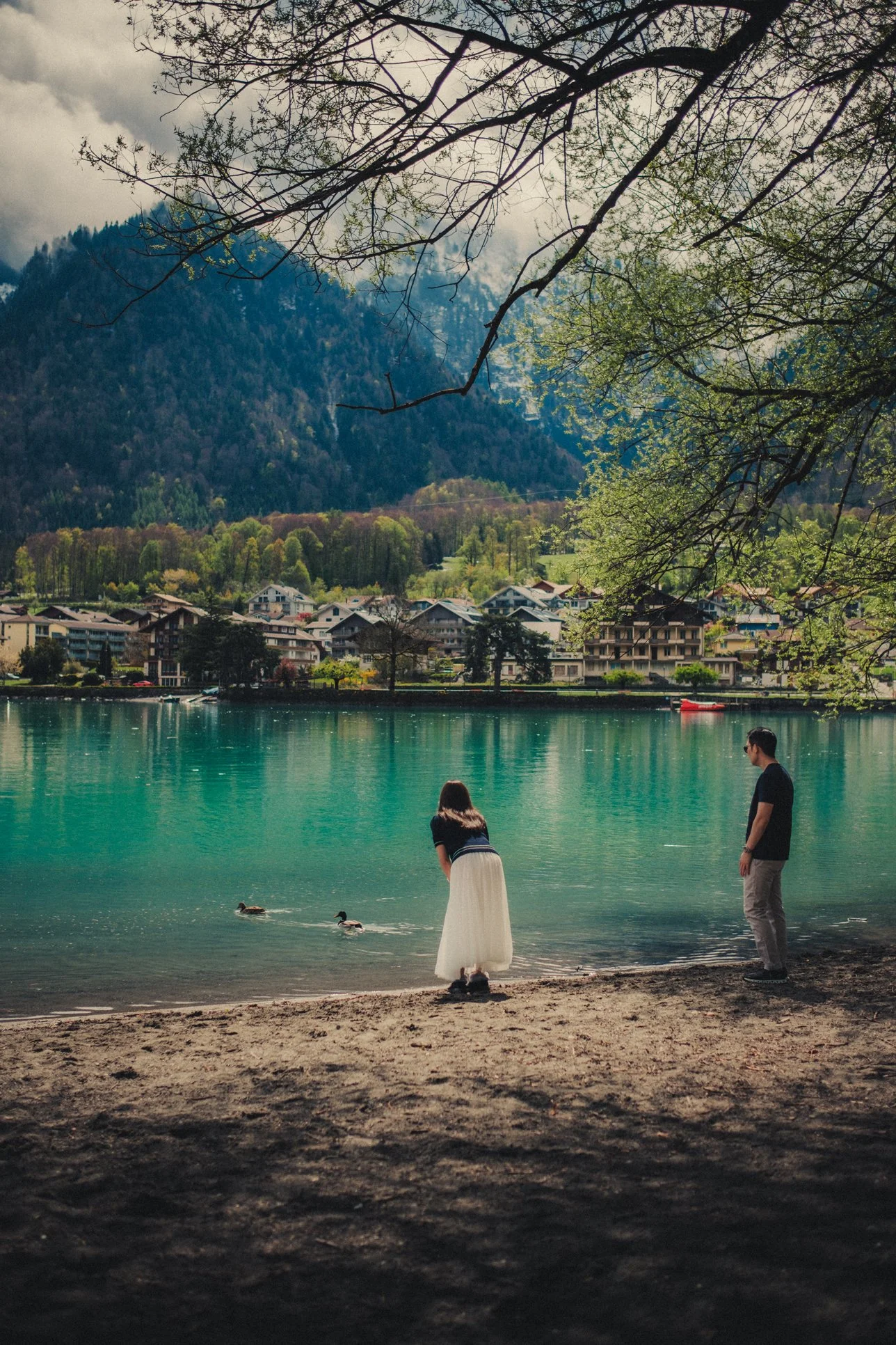 Couple standing beside the turquoise waters of Lake Brienz in Switzerland.