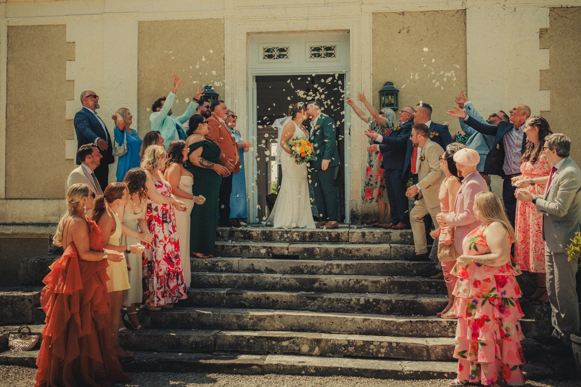 bride and groom showered with flower petals threw by guests at the chateau la gauterie