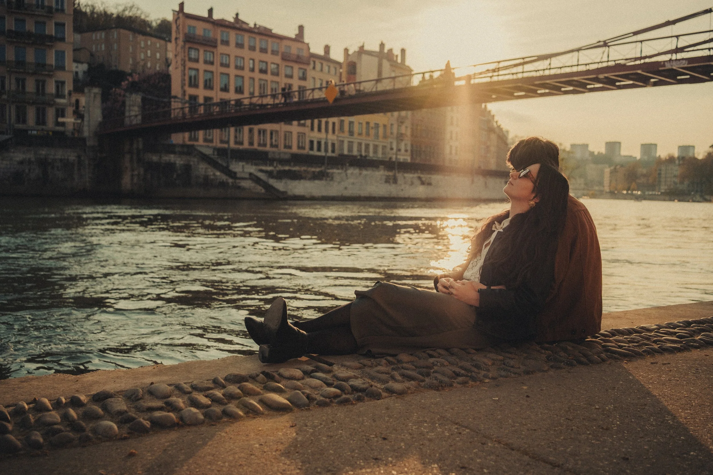 Couple enlacé assis sur les quais de Saône à Lyon sous la lumière dorée.