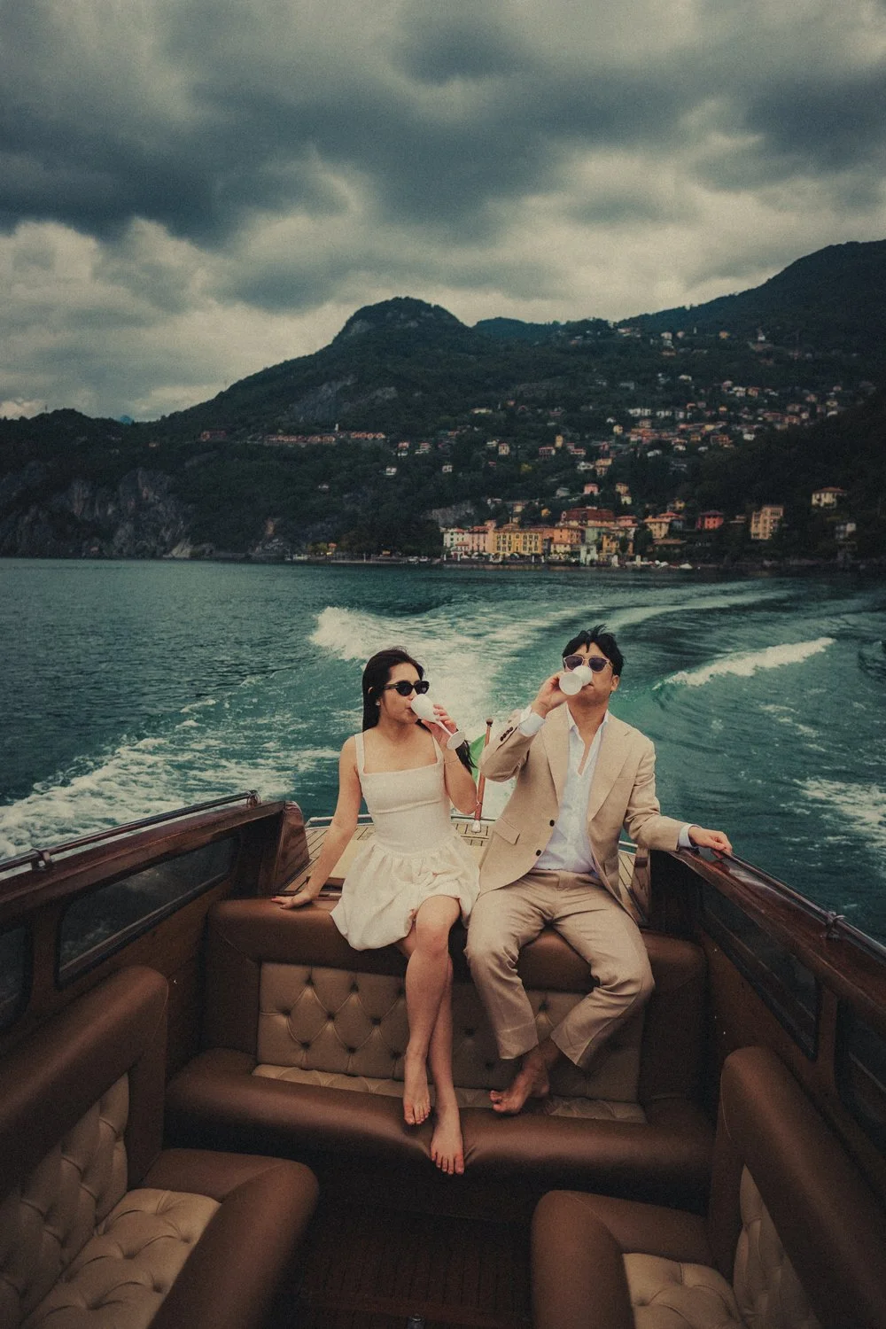 Couple sipping champagne on the wooden boat cruising on the lake Como.