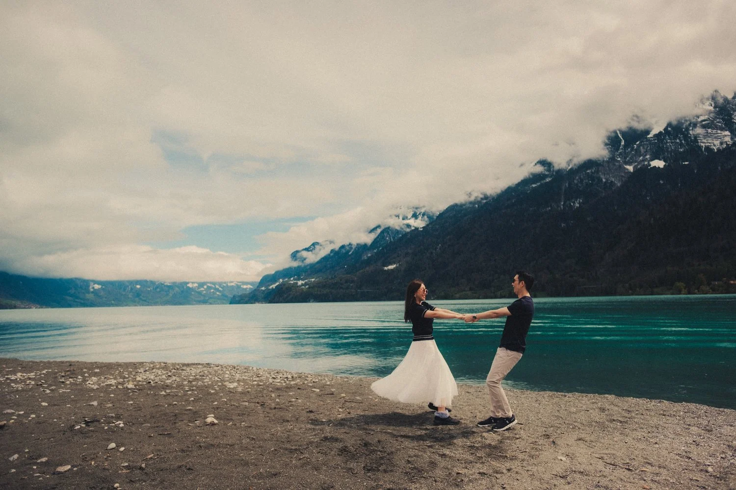 Candid honeymoon moment at Lake Brienz with the Swiss Alps in the background.