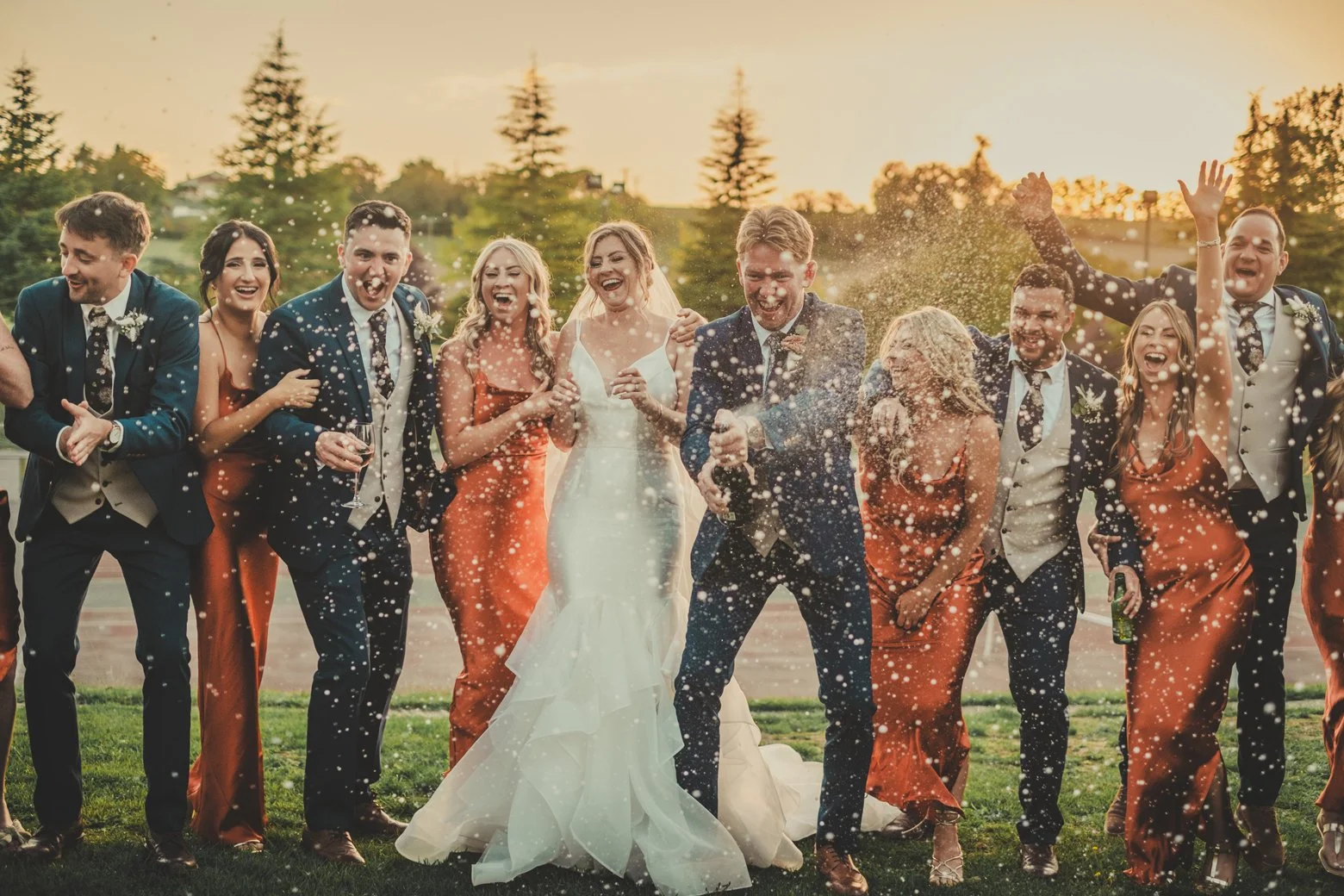 bride and groom with their friends having a champagne shower moment at their wedding at manoir de longeveau