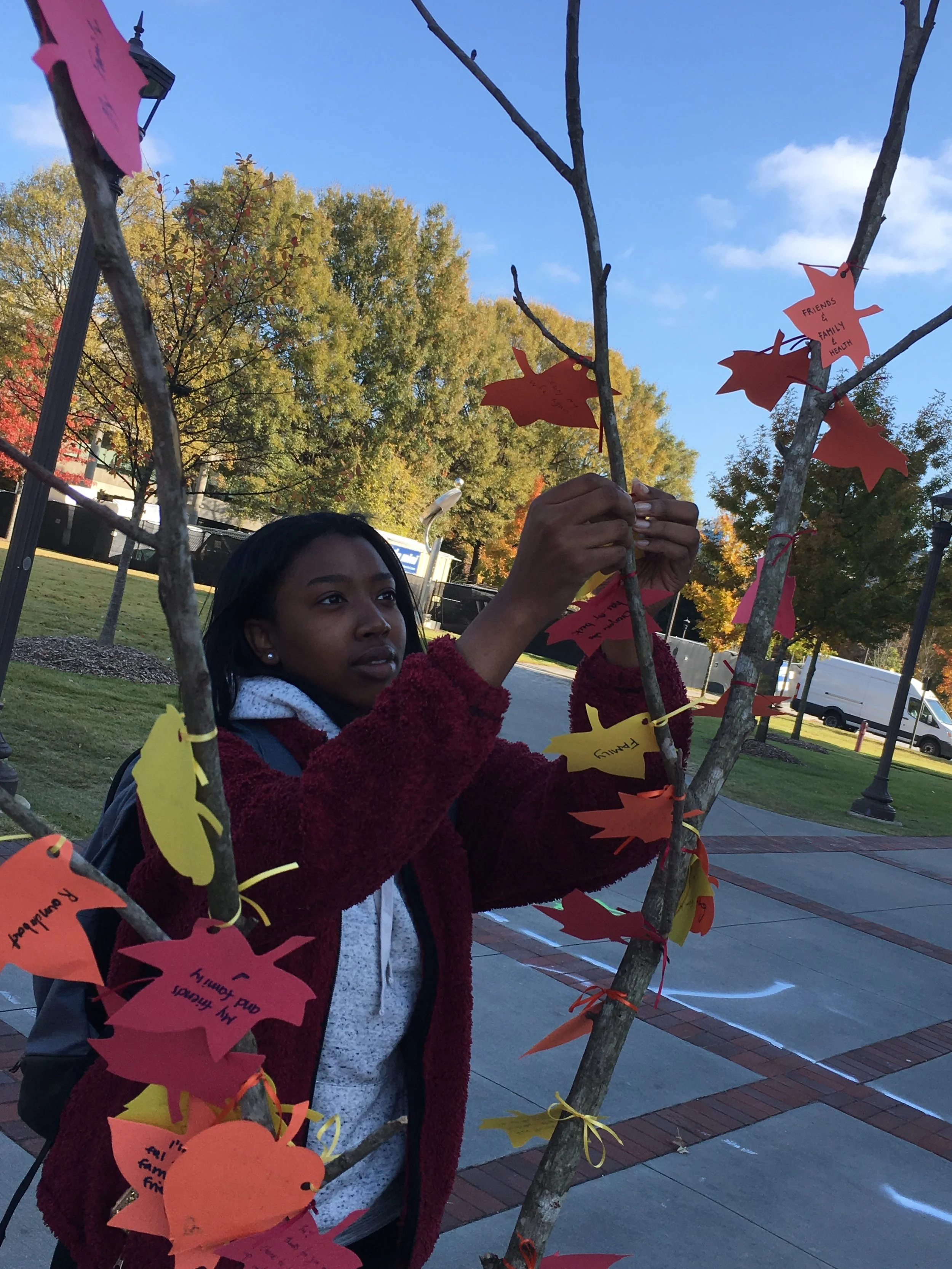 A girl hanging a leaf on the tree.