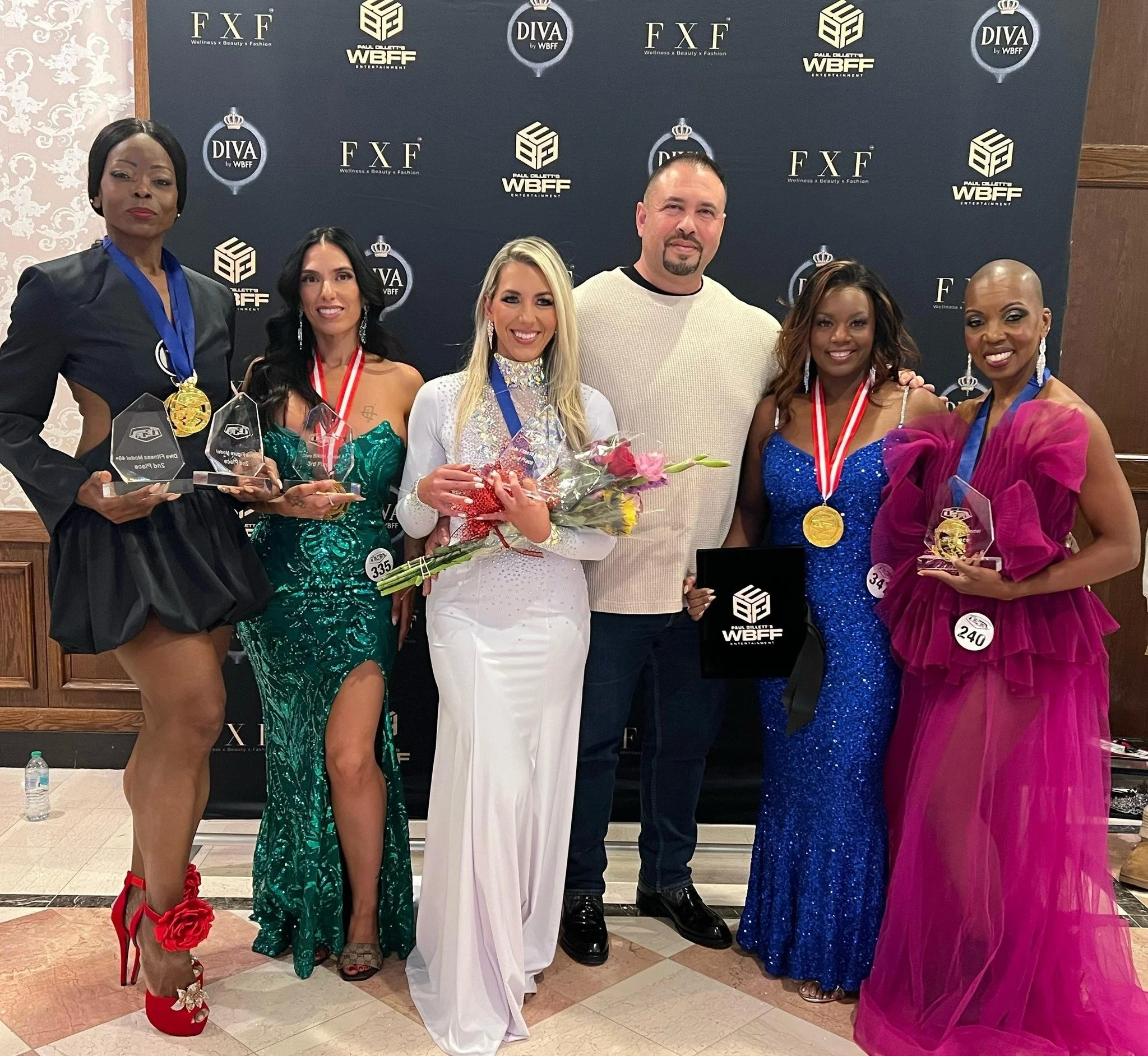 Team NXT LVL WBFF champions with coach Rafael Moret and WBFF Pro posing coach Lais Villamur