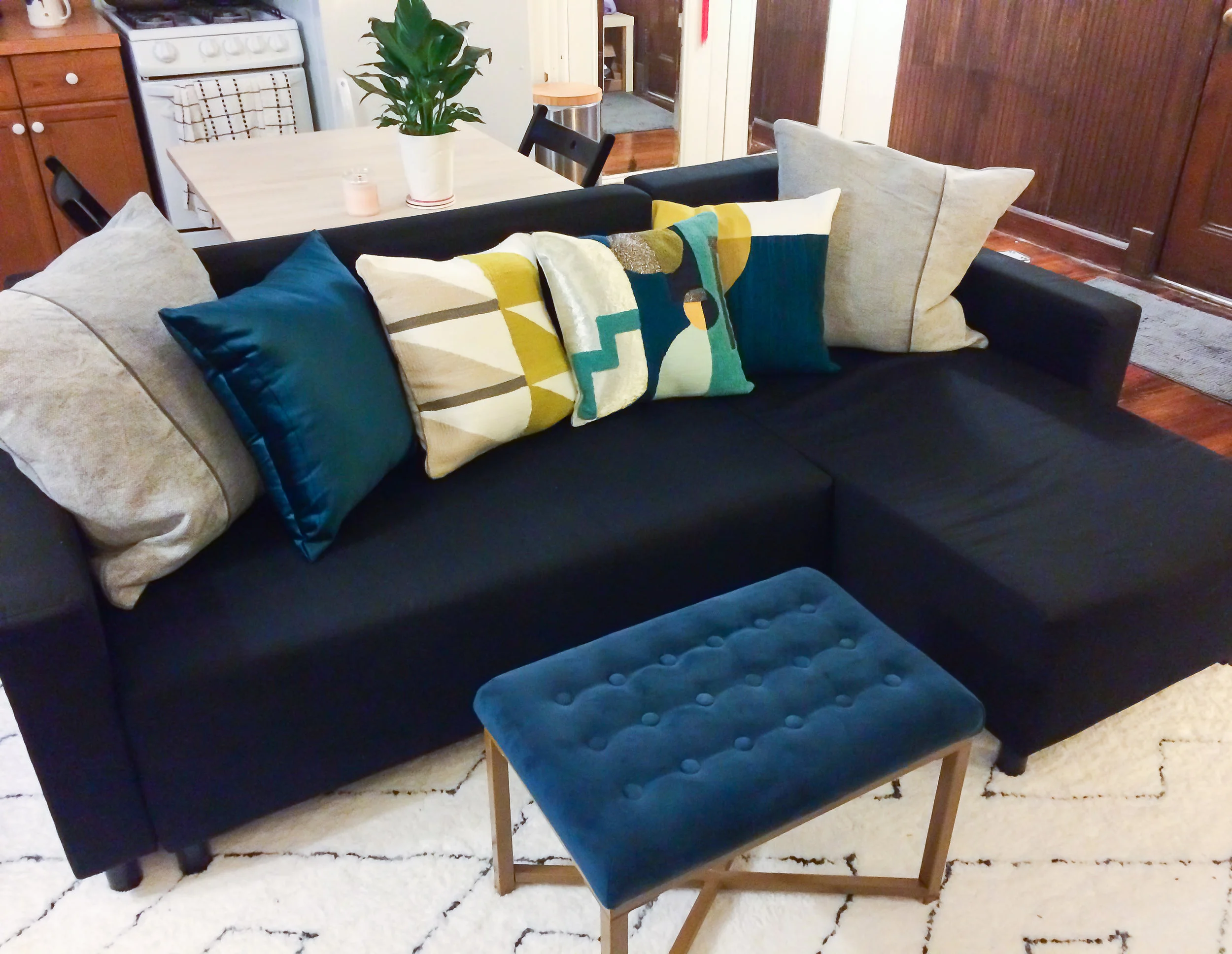 Peraza Hand-Tufted White Area Rug from Wayfair , Rectangle Velvet Tufted Ottoman in Midnight Blue from Target , Cotton Canvas Pillow in Iron from WEst Elm , Crewel Overlapping Shapes Pillow from West Elm , Embellished Deco Shapes Pillow from West Elm , Cotton Luster Velvet Pillow in Regal Blue from WEst elm ,