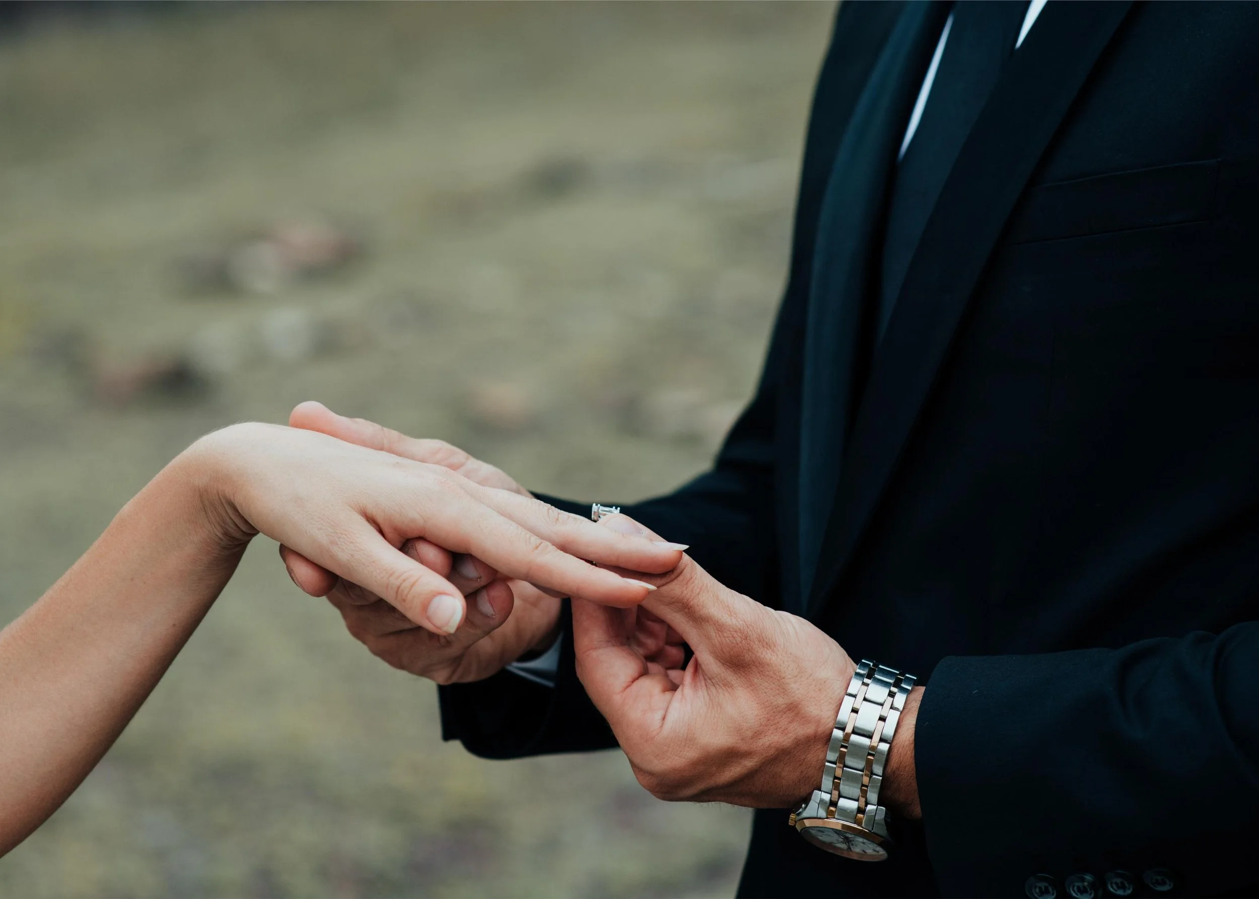 A man in a black suit holding a woman's hand during a wedding ceremony.