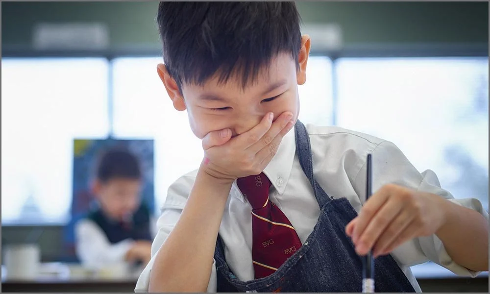 private school child covering giggles while painting.jpg