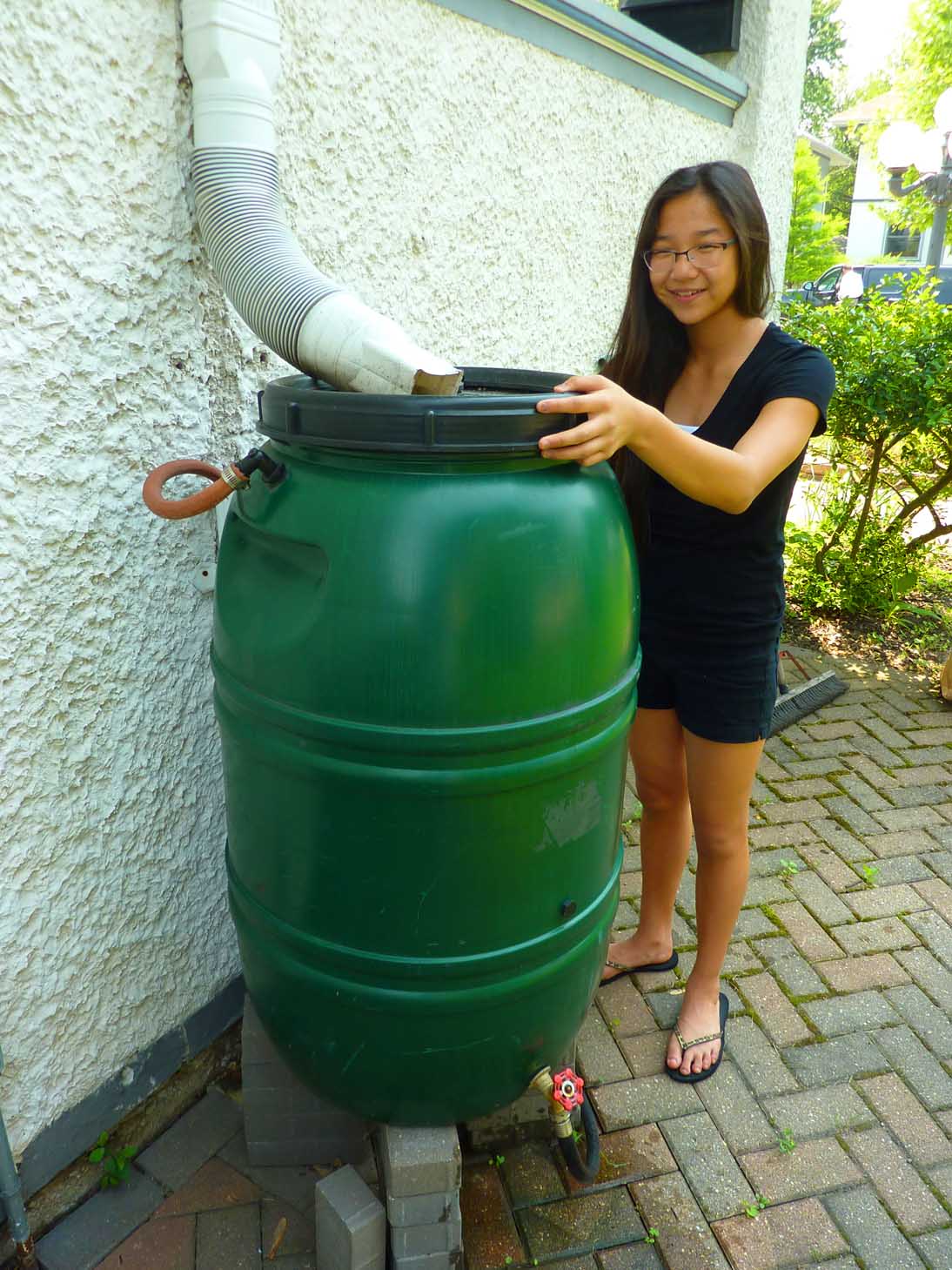 A girl checks her rain barrel.