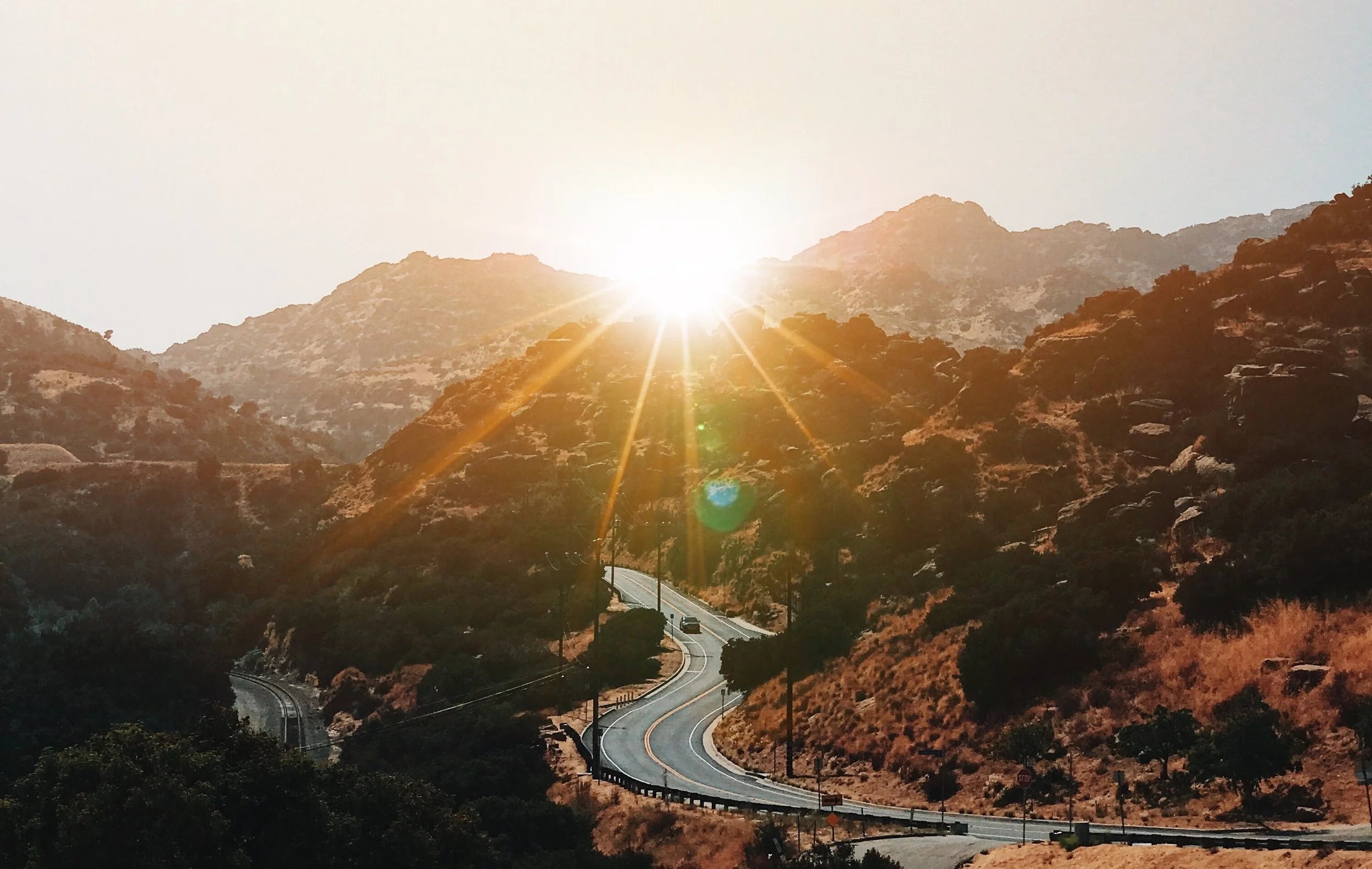 Sunset over a winding Los Angeles mountain road on Madeleine Perez’s contact page.