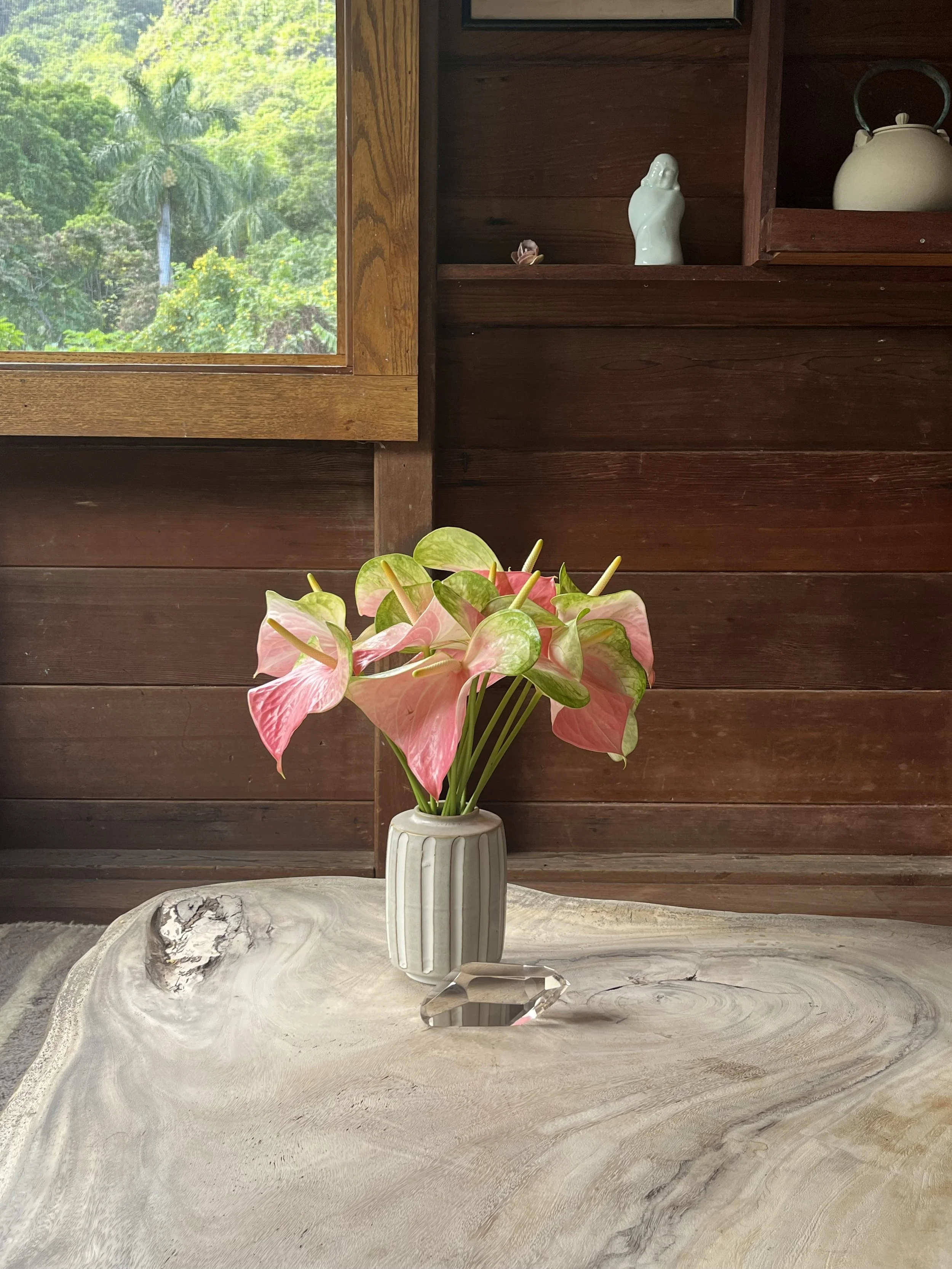 a vase of anthuriums on a wooden table