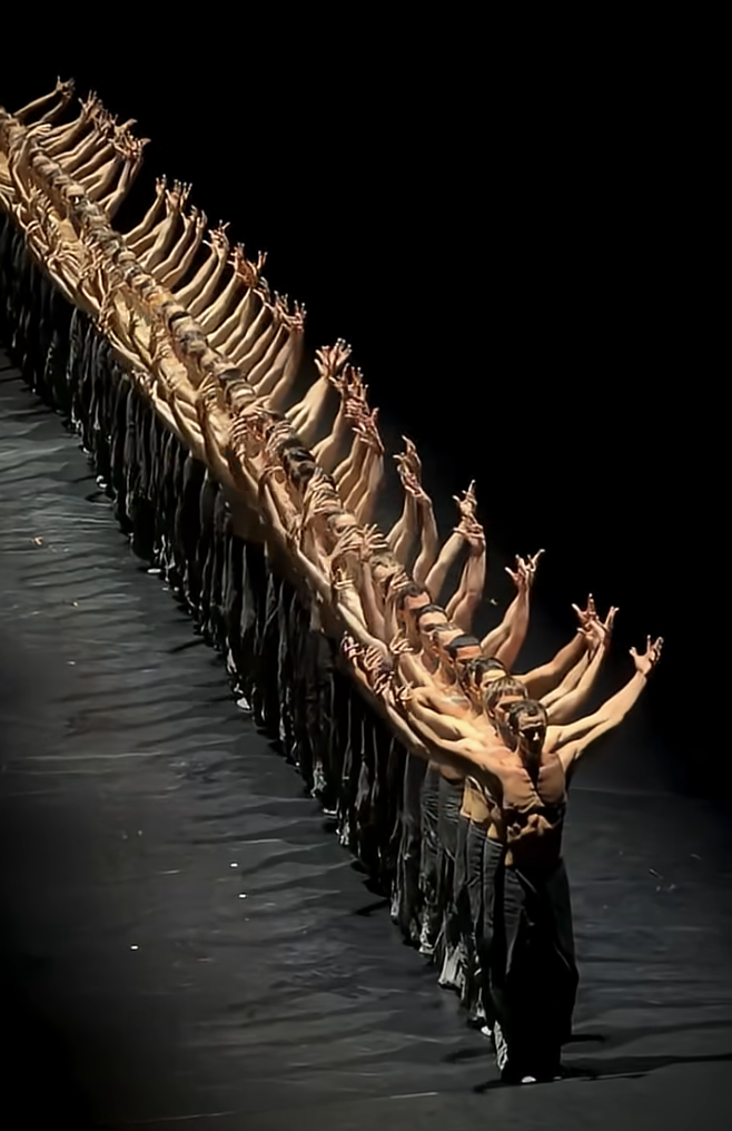 A line of ballet dancers with arms extended