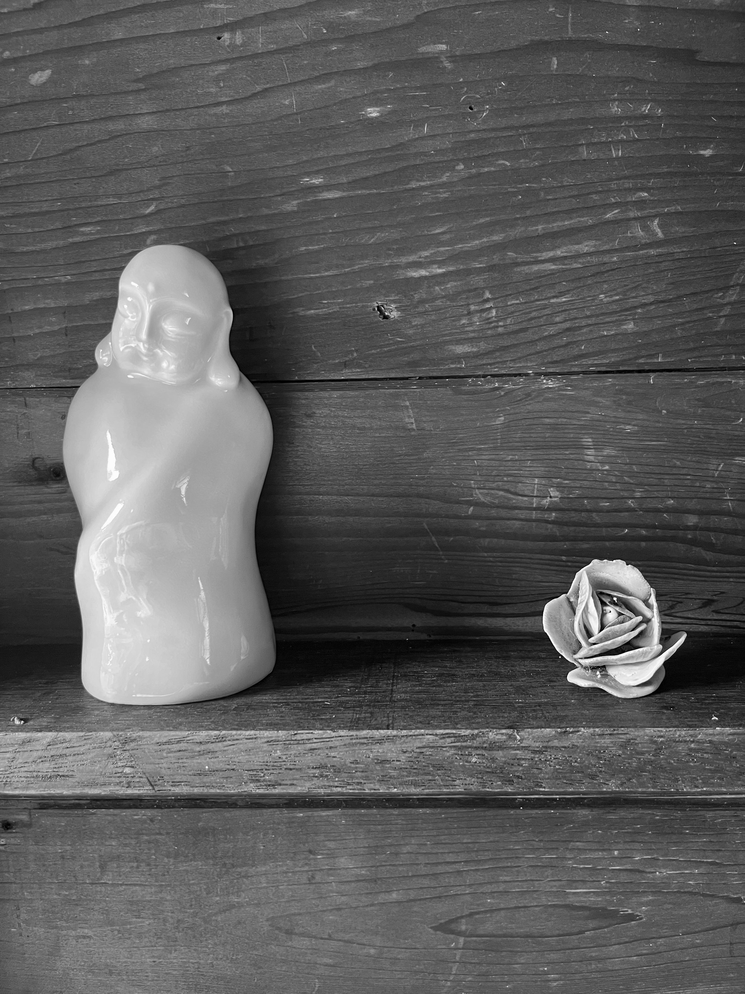 Small buddha statue on shelf with cermic rosette