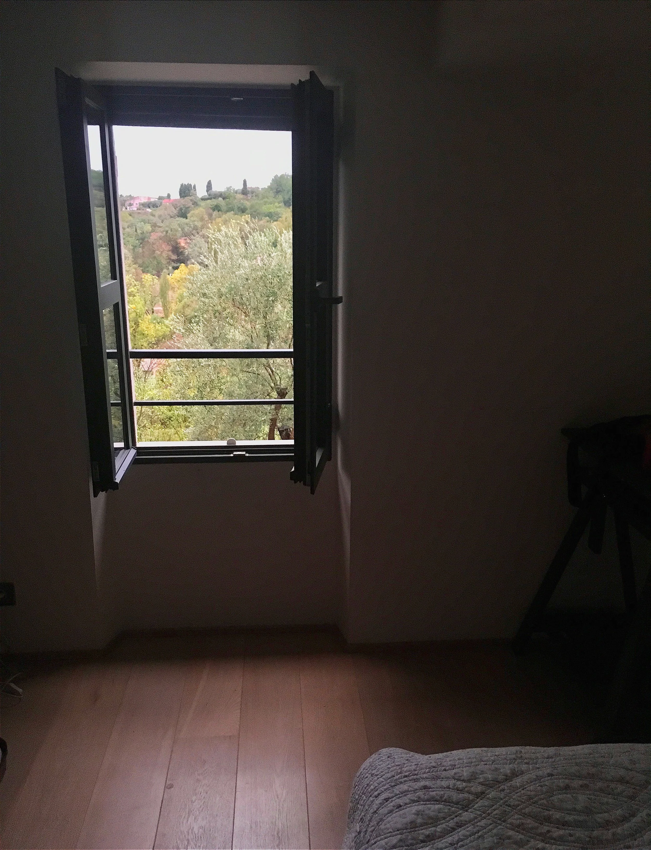 dimmly lit bedroom with a window looking out to the countryside