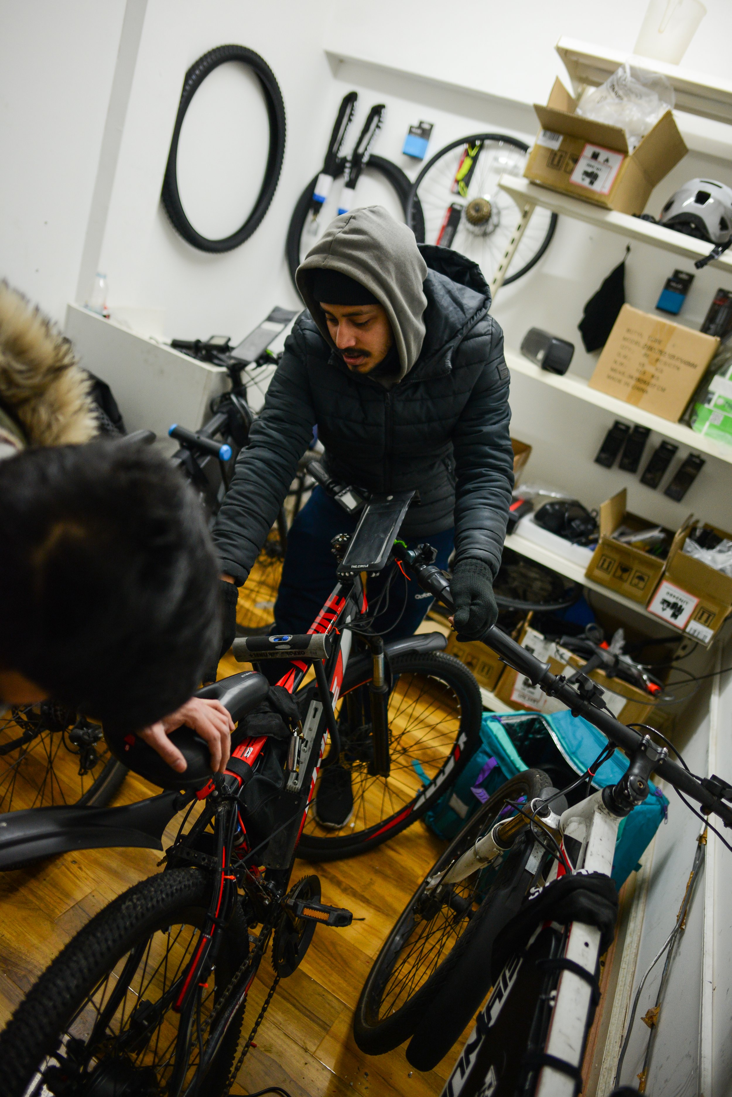  Faruk, 27, the owner of ‘Whitechapel Bikes’ garage and mechanics, helps Nurul to fix his bike 