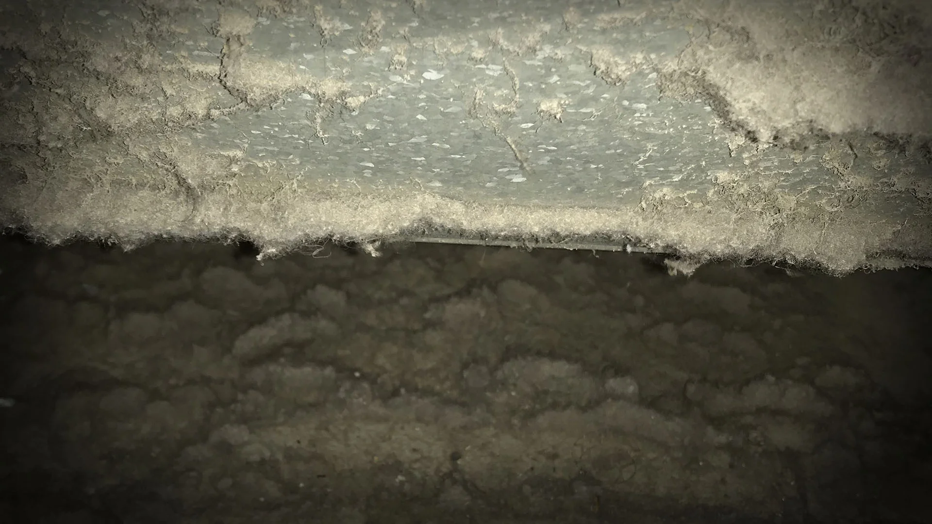 Heavy dust and debris accumulated inside a residential HVAC air duct before professional source-removal cleaning.