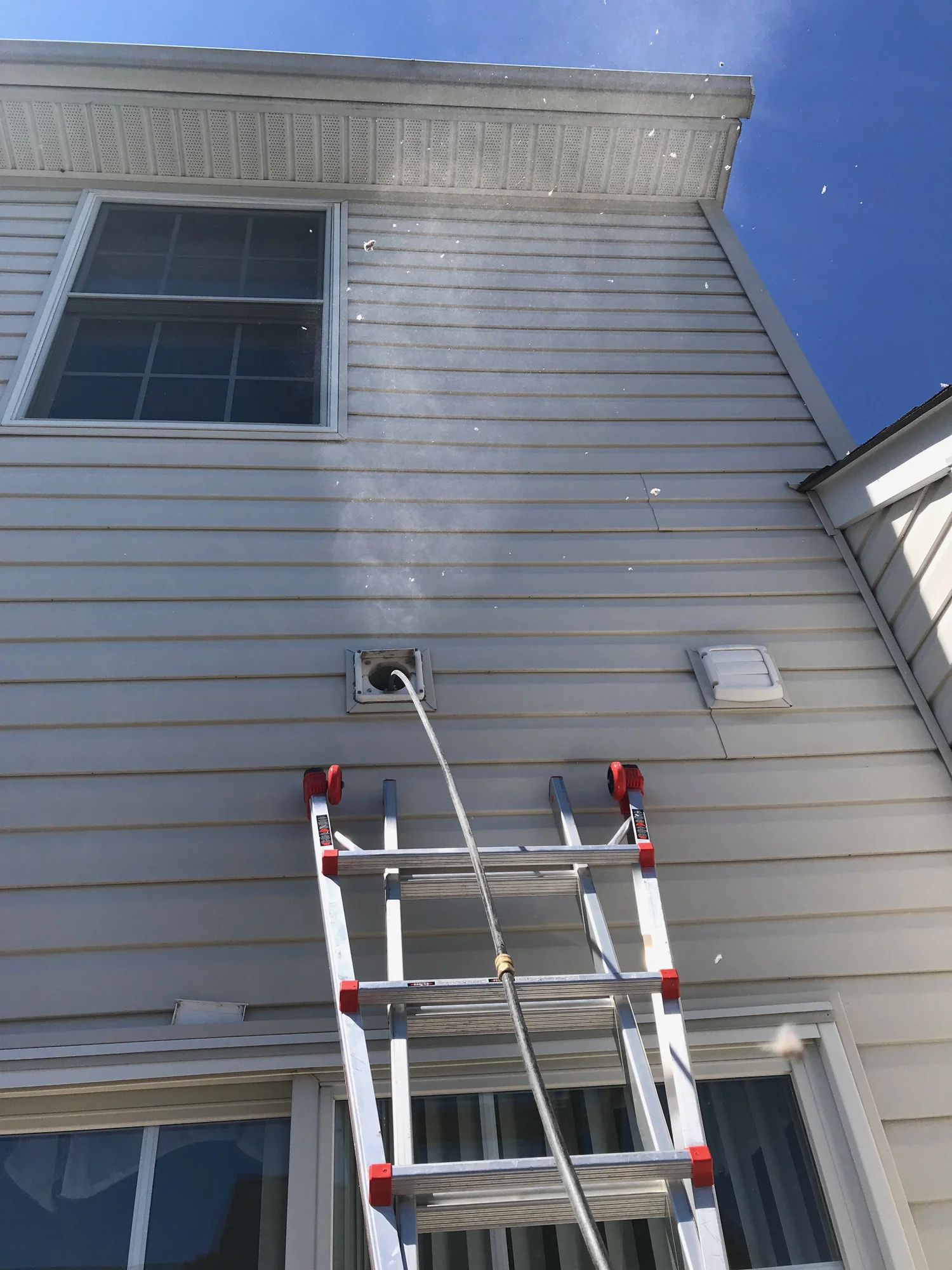 Cone-shaped plume of lint expelled from an exterior dryer vent during air-tool cleaning