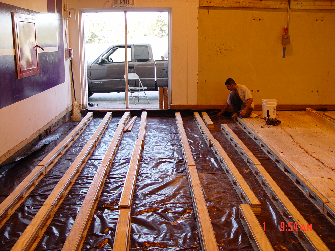 Sleepers over a moisture mitigation sheet membrane to support a hardwood sports floor