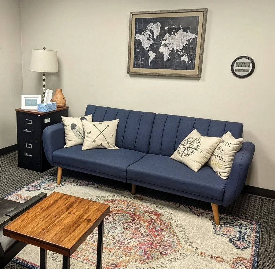Calm, professional therapy room at Iron City Counseling featuring a blue sofa, armchair, wood side table, soft rug, and neutral decor in a private counseling office in Birmingham, Alabama.