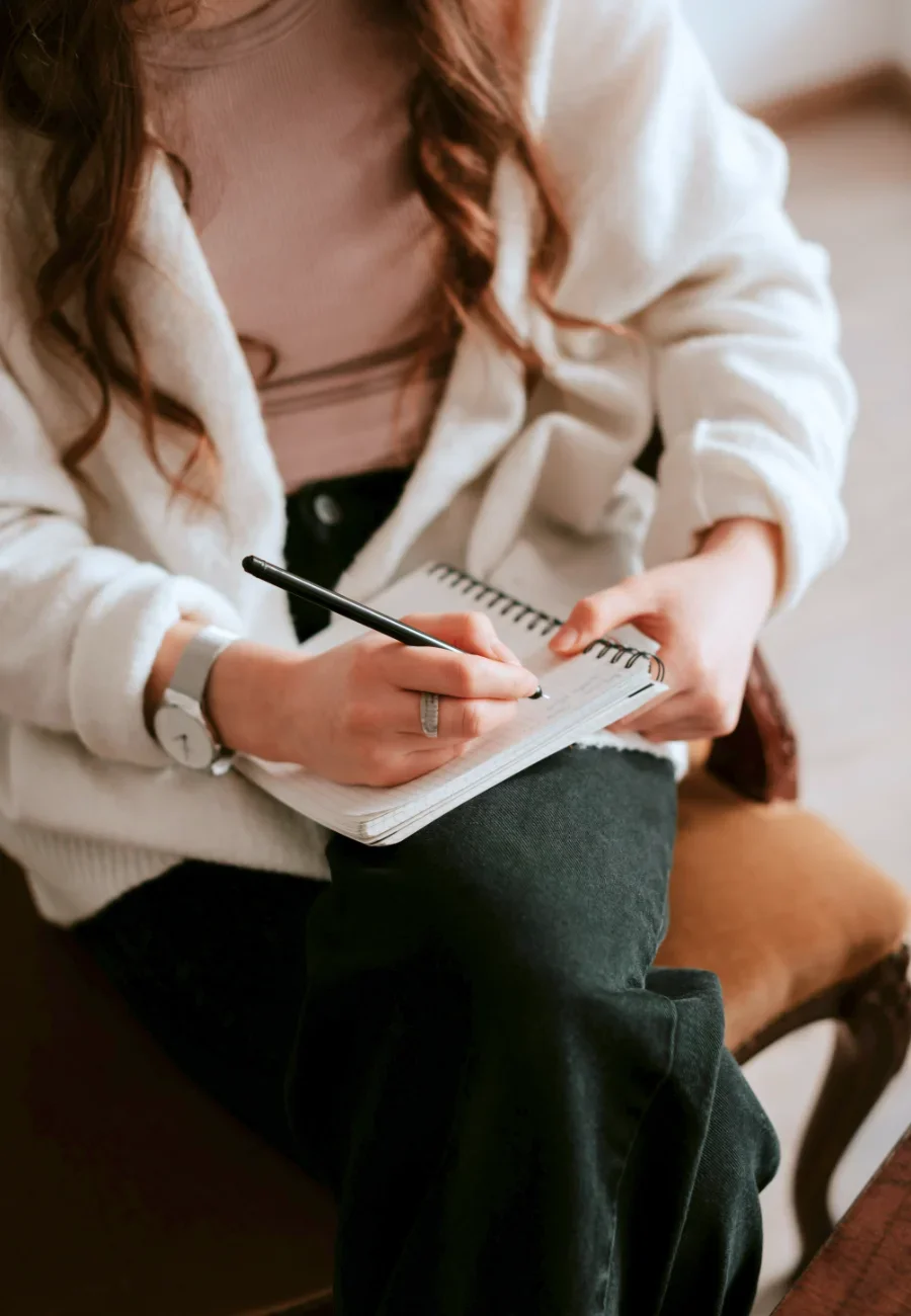 Mental health therapist writing notes in a notebook while seated in a counseling office, representing clinical documentation and professional responsibilities at Iron City Counseling in Birmingham, Alabama.