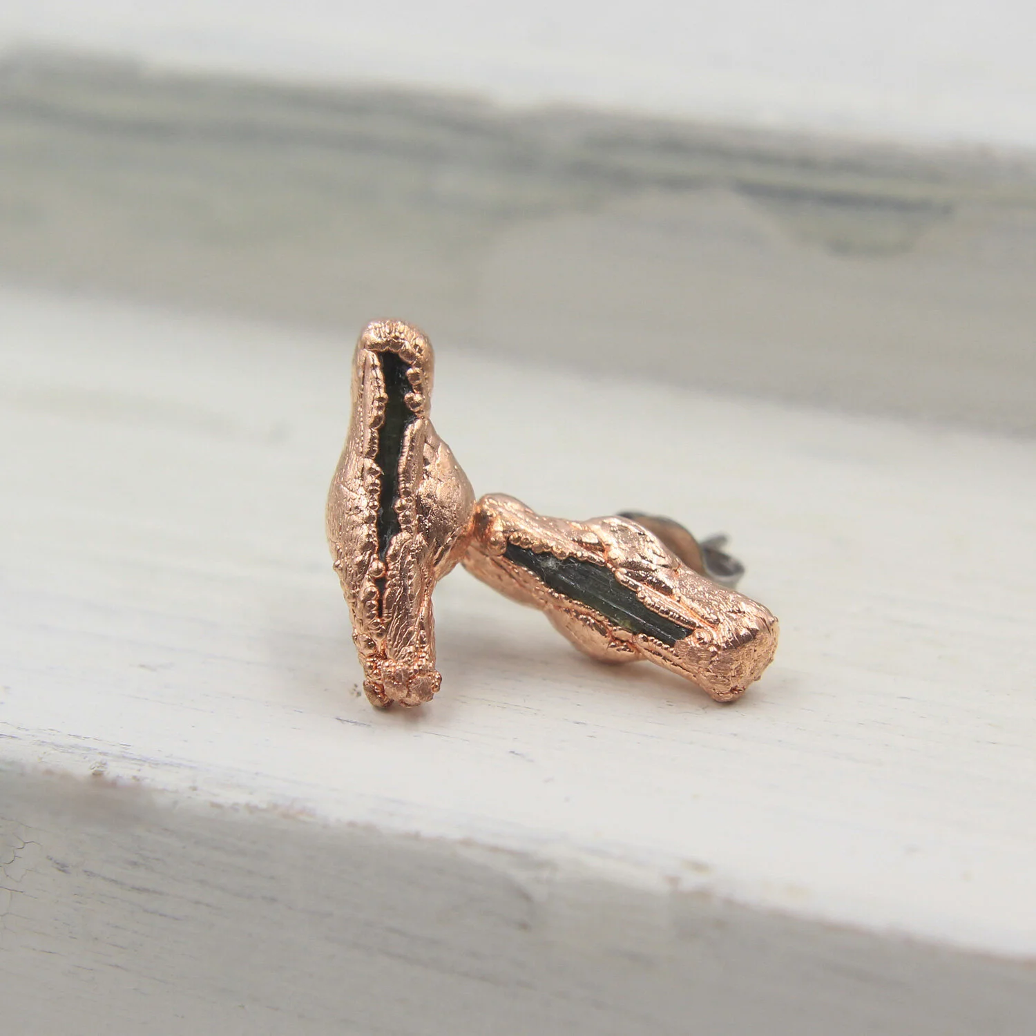 Uvite tourmaline copper stud earrings on display