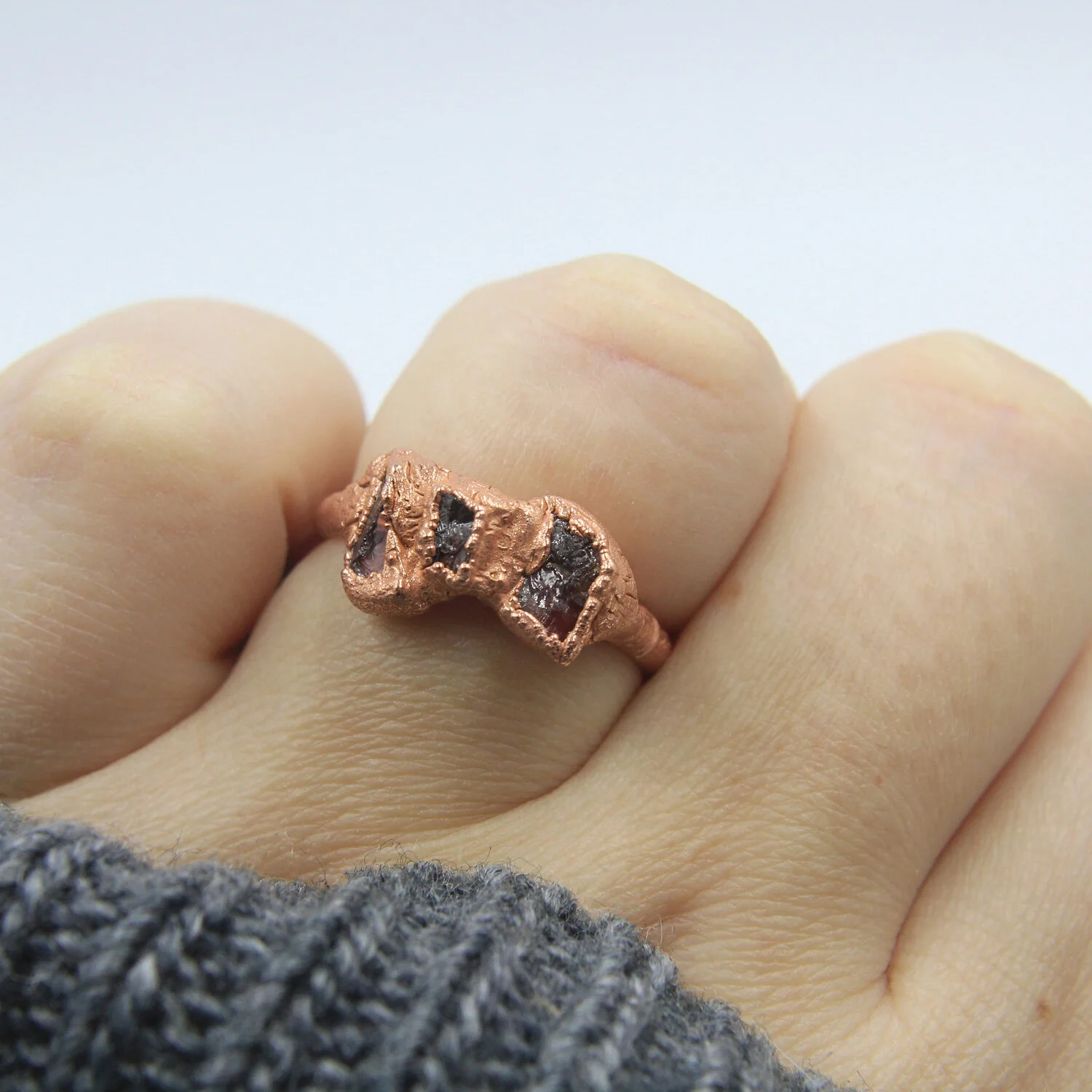Garnet three-stone electroformed copper ring on hand