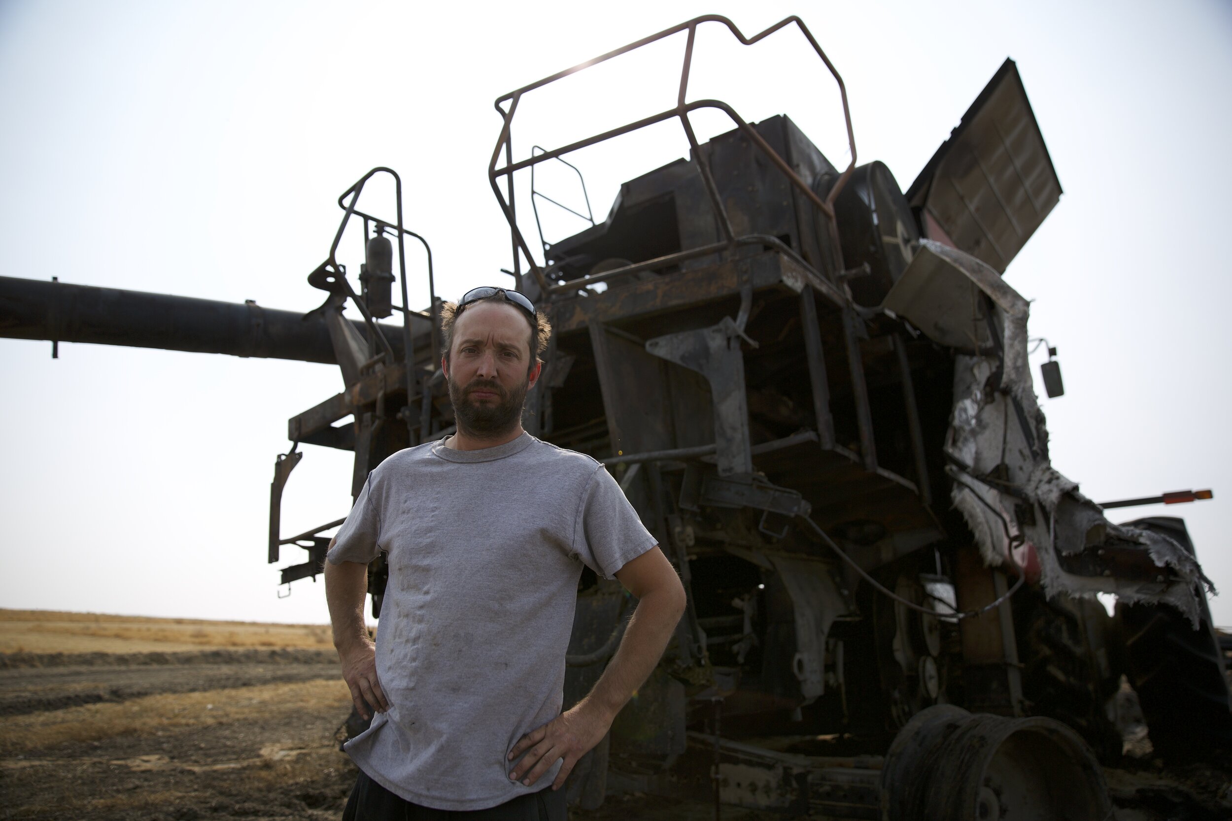 Farmland - Stuart Leonard with his combine, which was destroyed by fire while harvesting.jpg