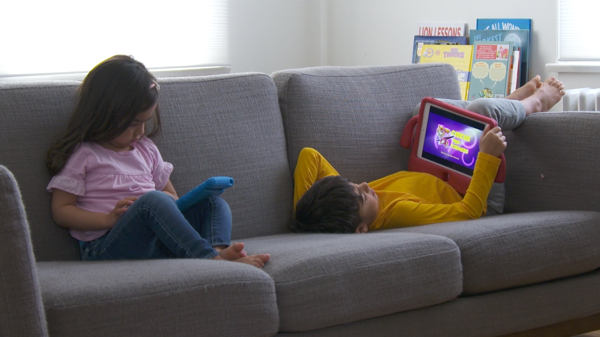 kids side by side on couch with ipads feet hanging over copy.jpg