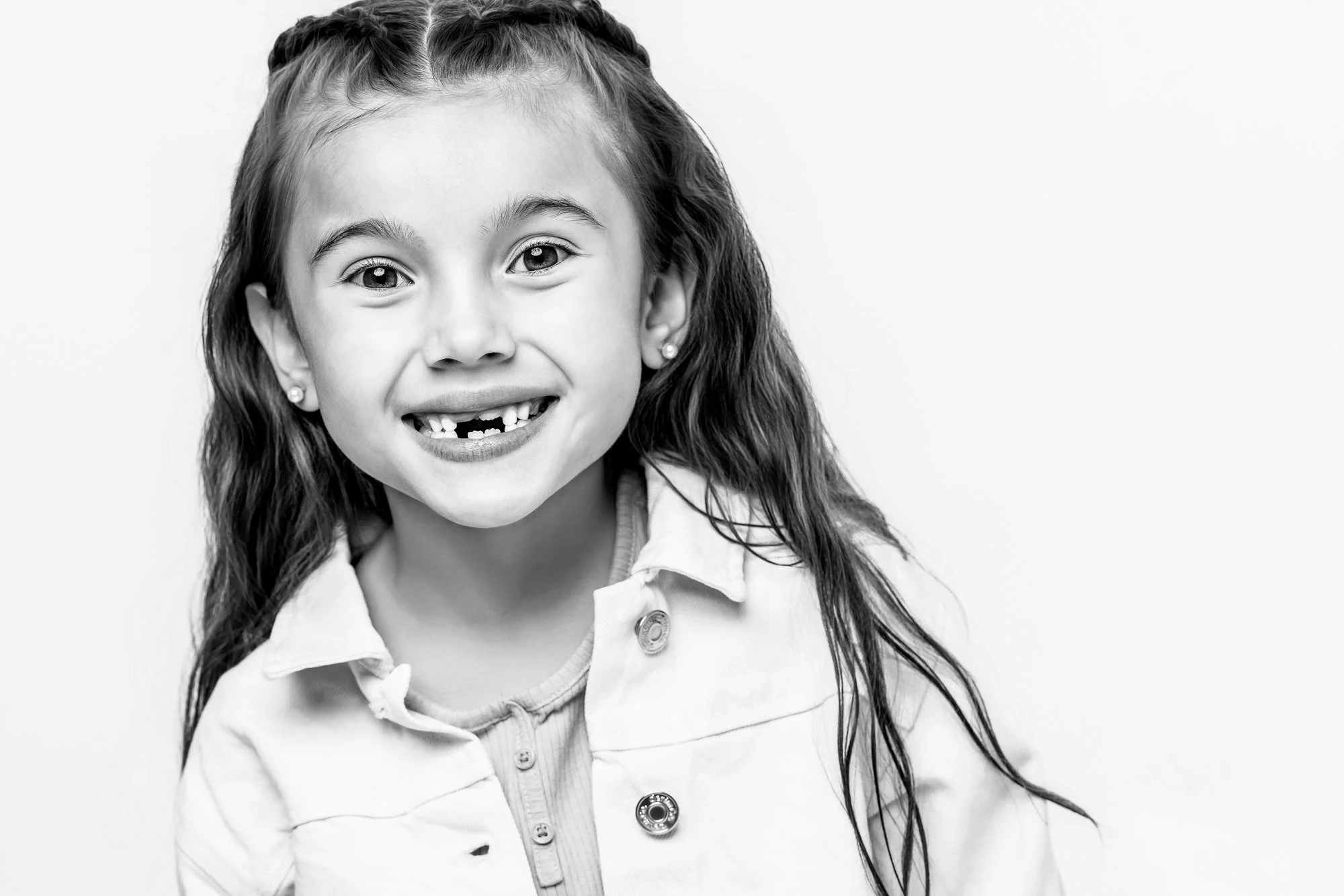 Black and white studio portrait of a smiling girl with missing front teeth, McAllen TX children's portrait photographer