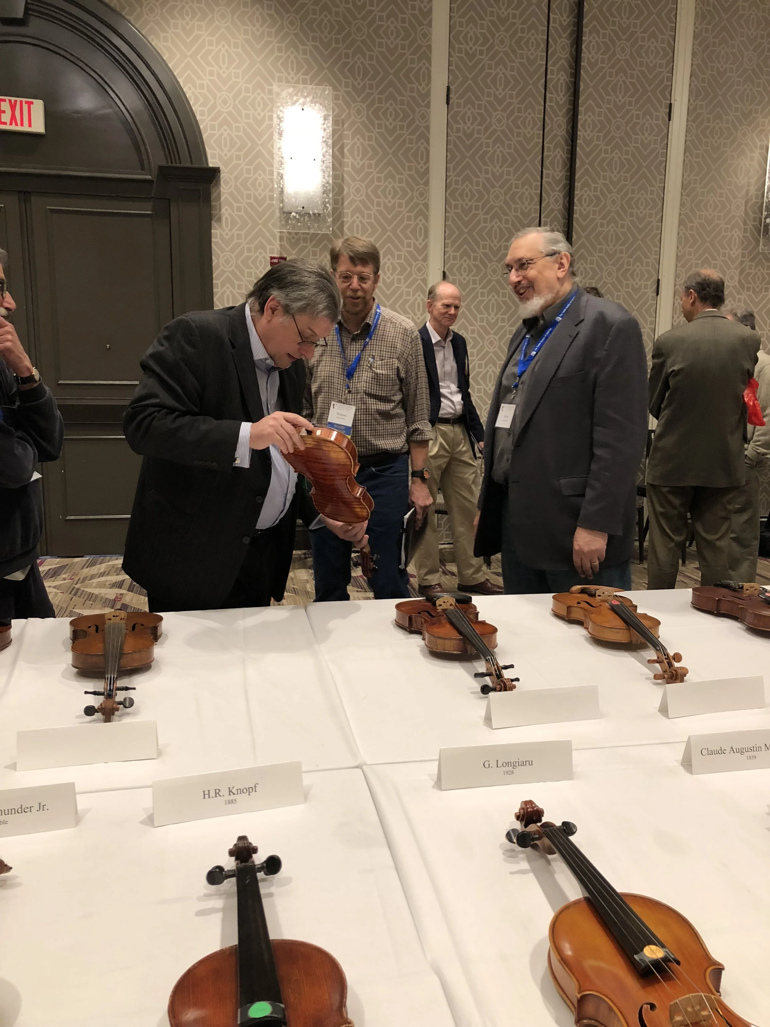 Phillip Kass and David Bromberg discuss a violin at the exhibit of American Violins on Display at the Violin Society of America (VSA) Convention in Washington DC in November 2017.