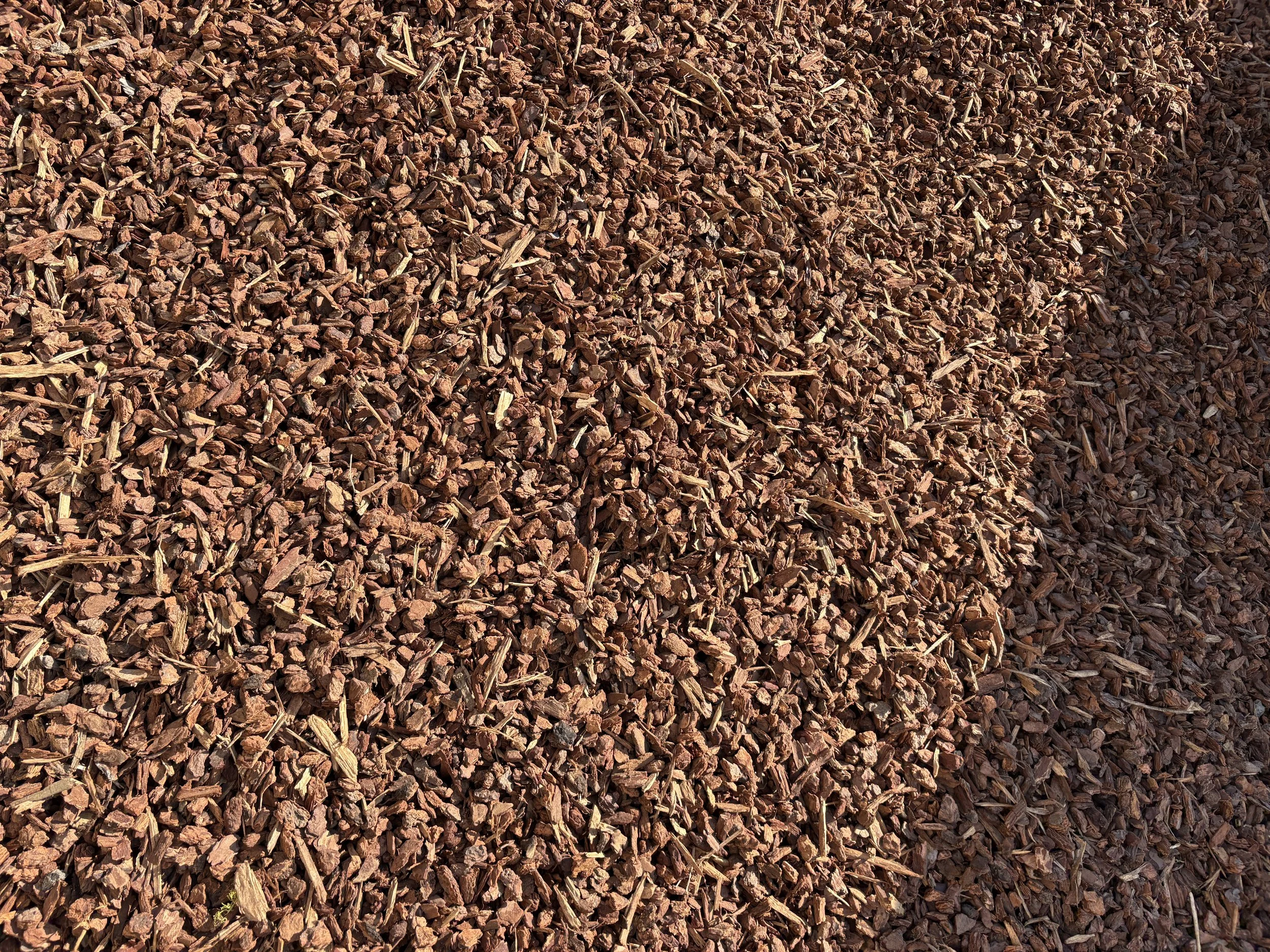 Close-up of reddish-brown wood mulch or bark chips on the ground.