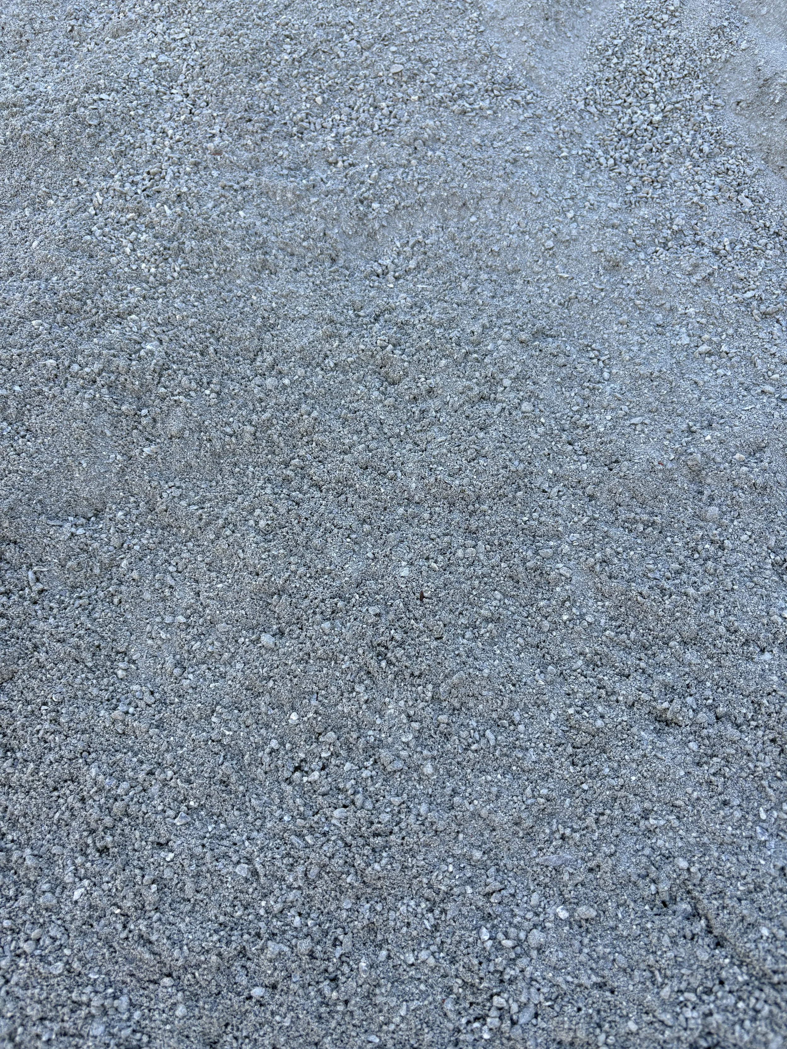 Close-up of a sandy, gravelly surface with small pebbles and fine sand particles.