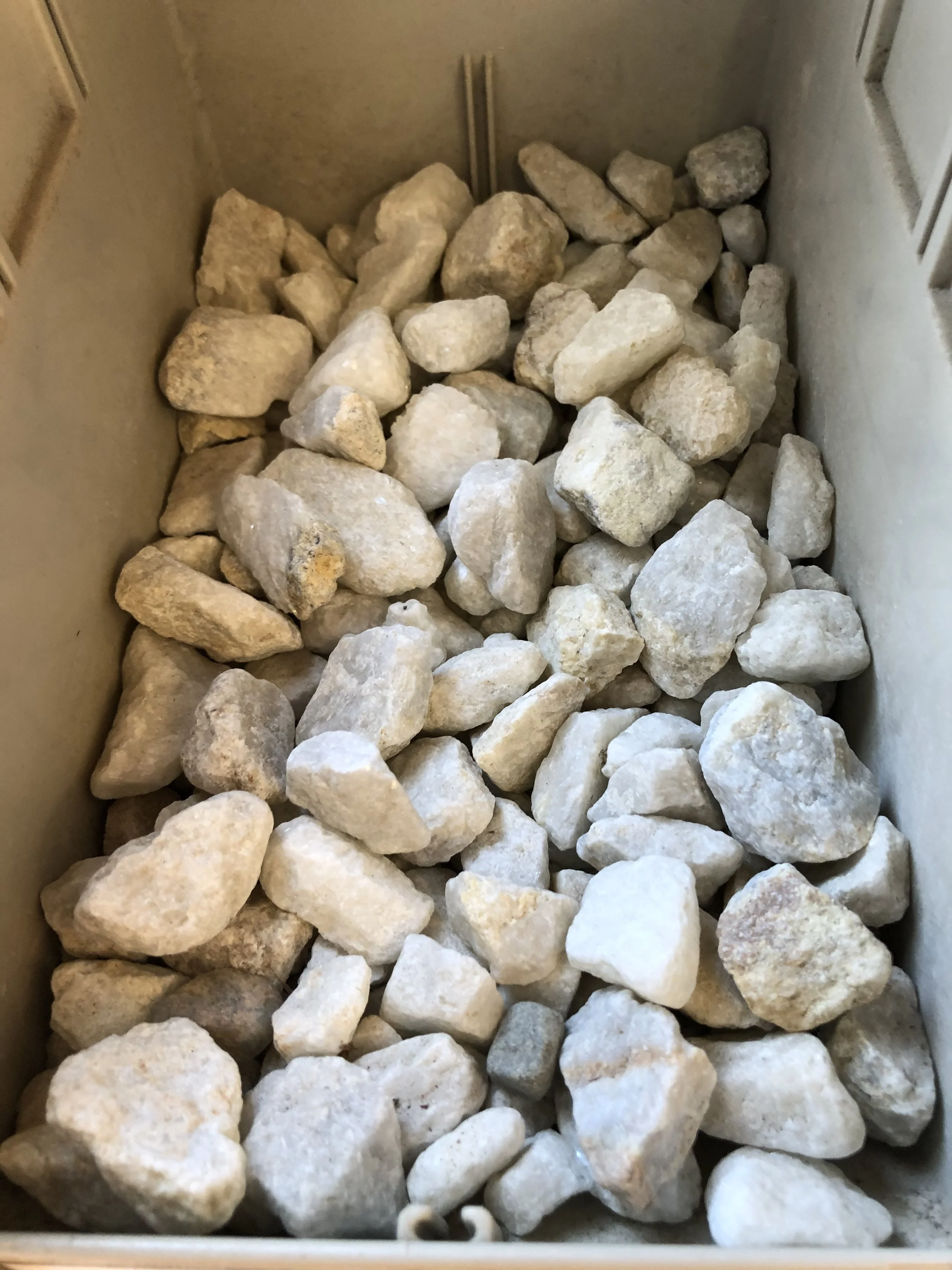 A container filled with irregularly shaped small white and beige rocks.