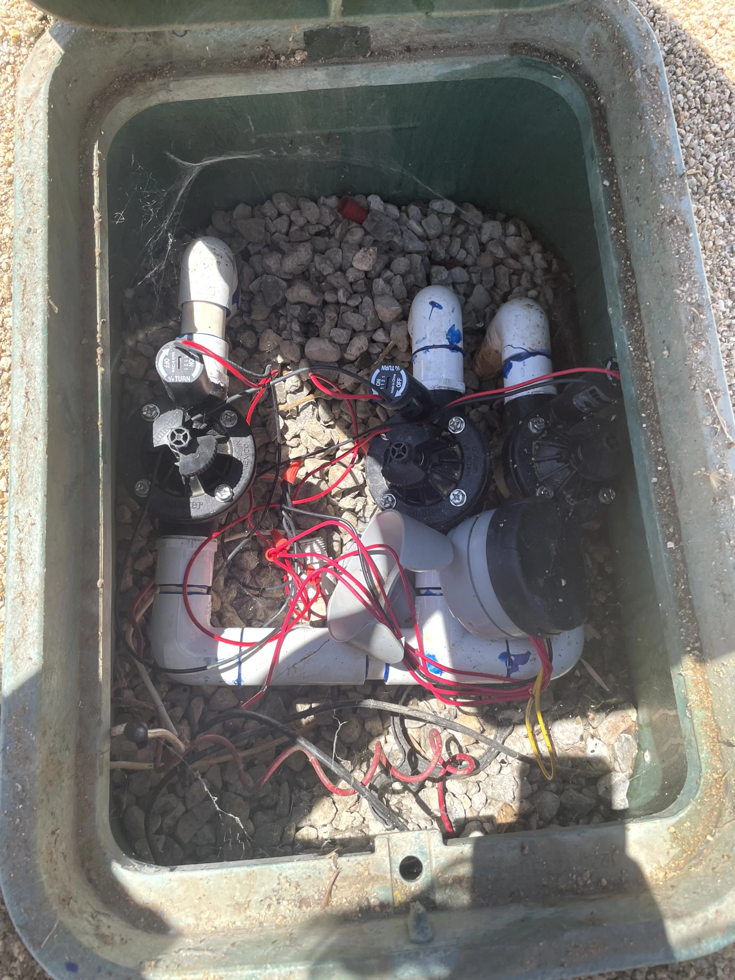 Inside of a pool control system box with various plumbing pipes, wiring, and electronic components.