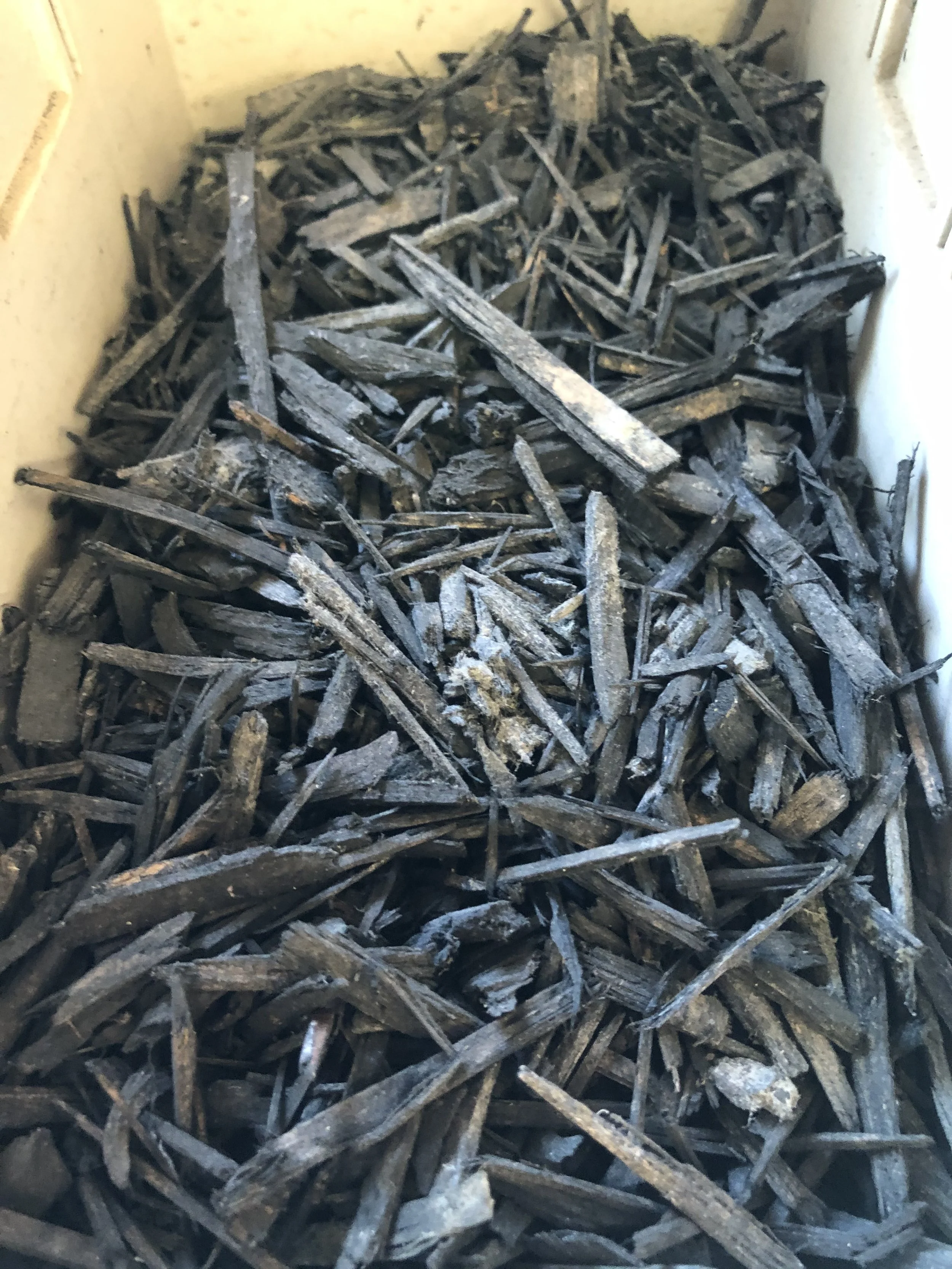 A large collection of old, weathered, and broken wooden sticks and pieces inside a container.