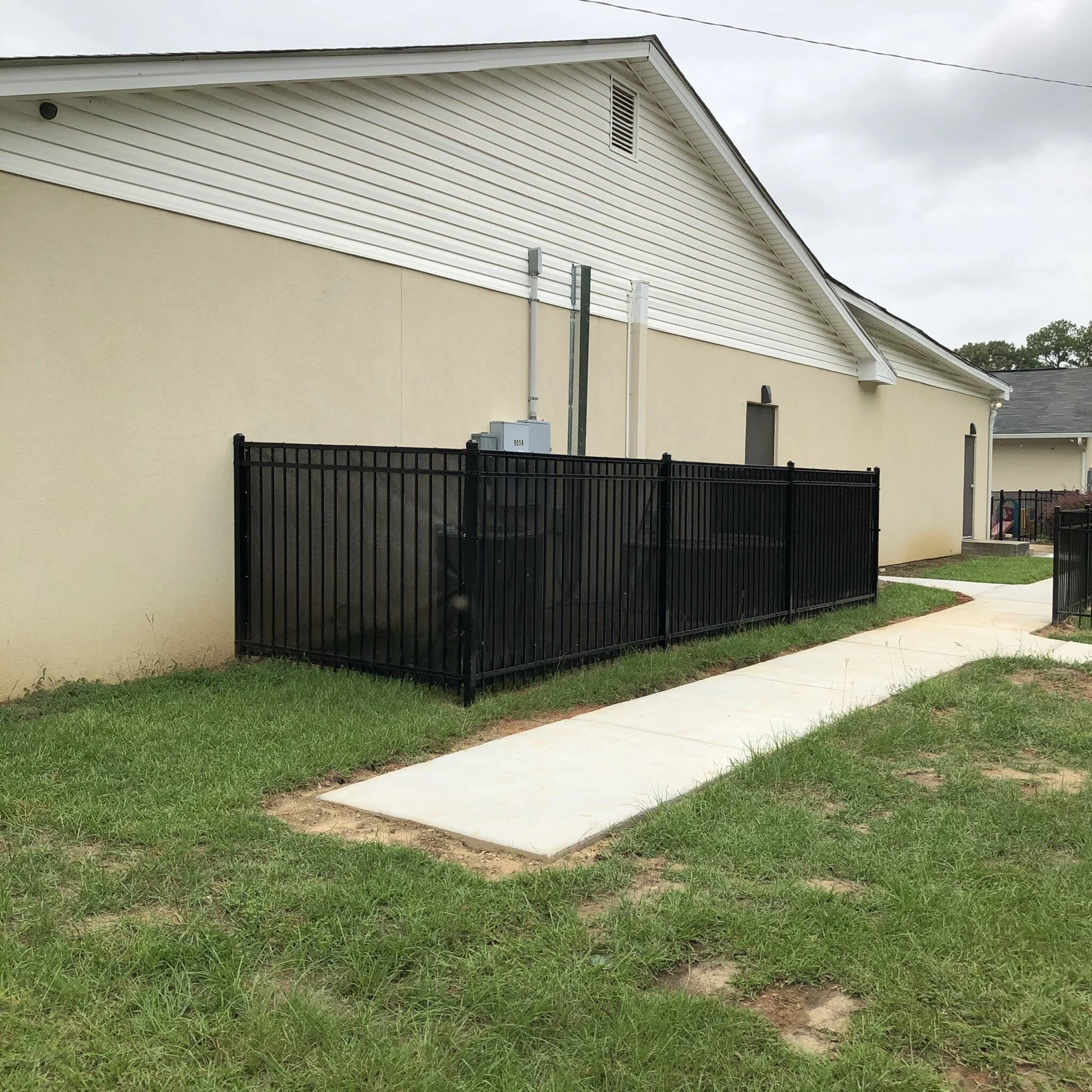 Ornamental aluminum A/C unit enclosure with black privacy screen.
