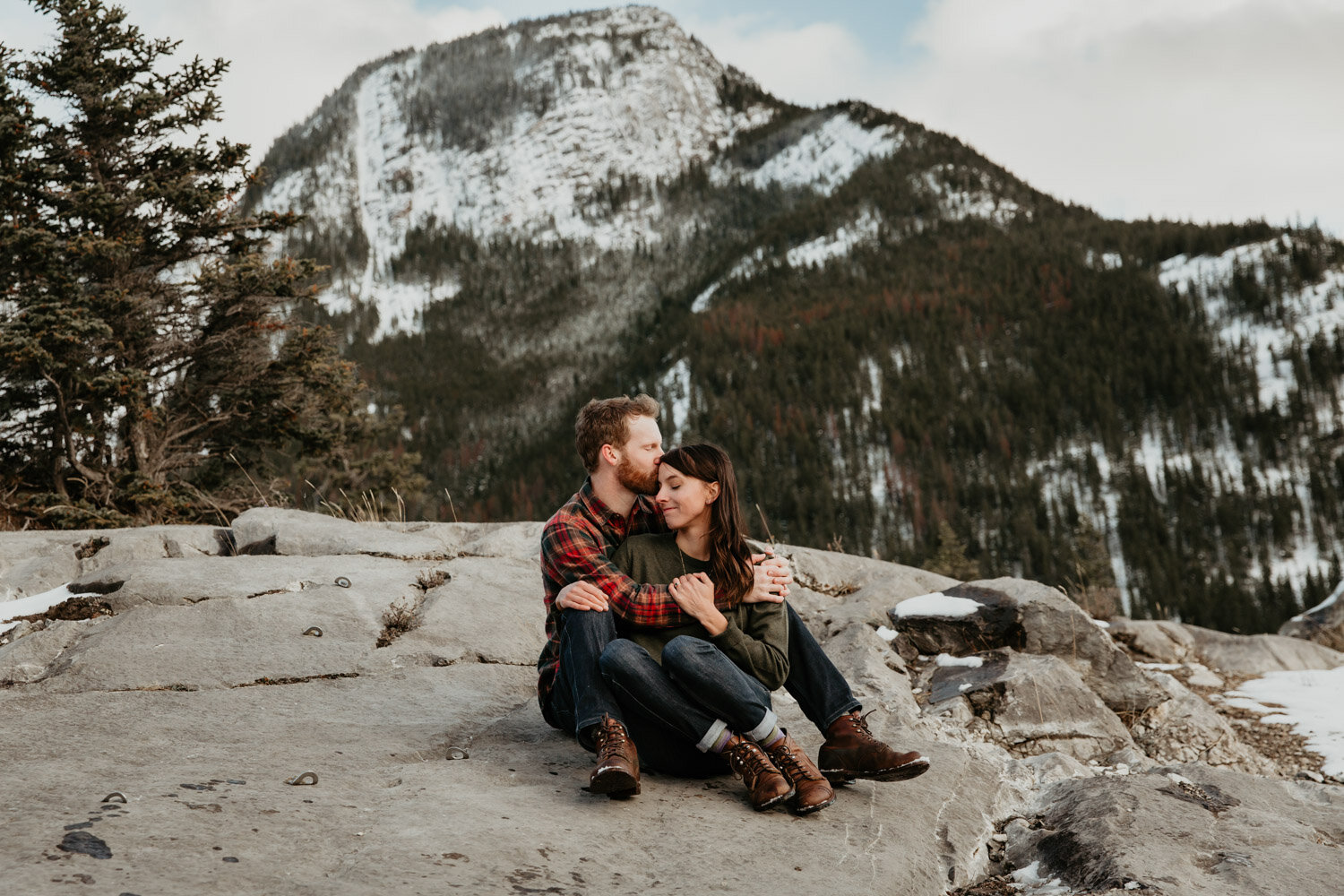Couple cuddling on rocks in the mountains | Jamie Robson Photography | Engagement Photographer in Jasper (Copy)