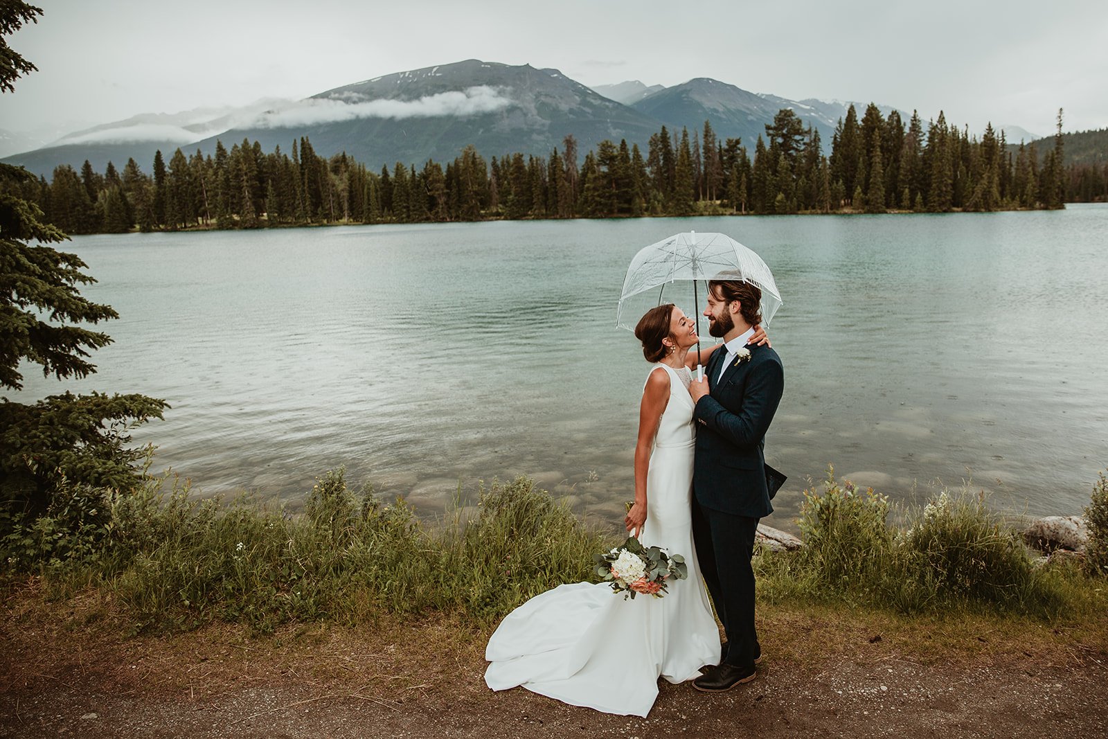Bride & Groom under umbrella at Lac Beauvert Jasper Park Lodge Wedding  | Jamie Robson Photography | Elopement & Wedding Photographer in Jasper (Copy)