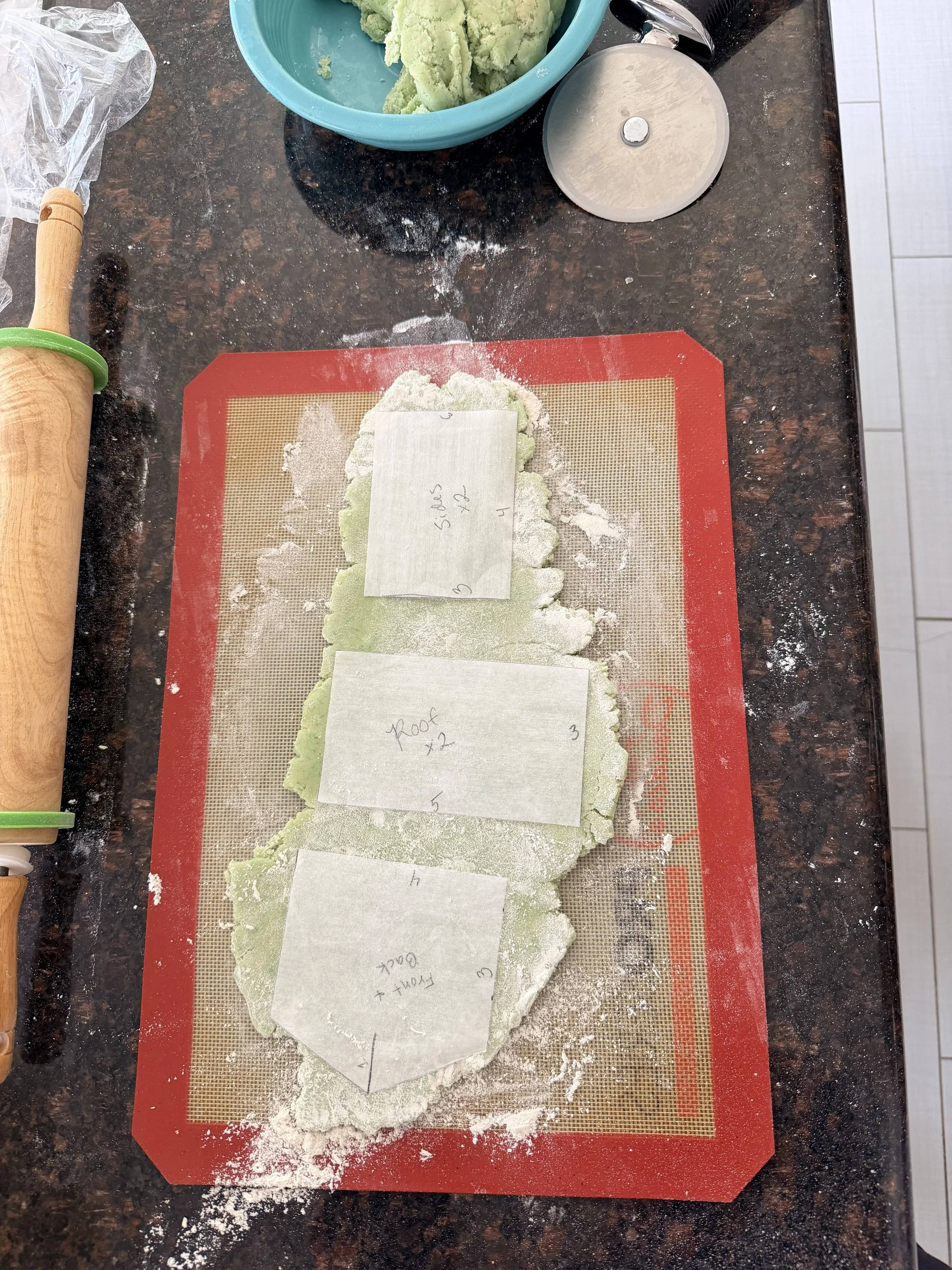 Rolled green sugar cookie dough with printable house template pieces for a St. Patrick’s Day leprechaun trap cookie house.