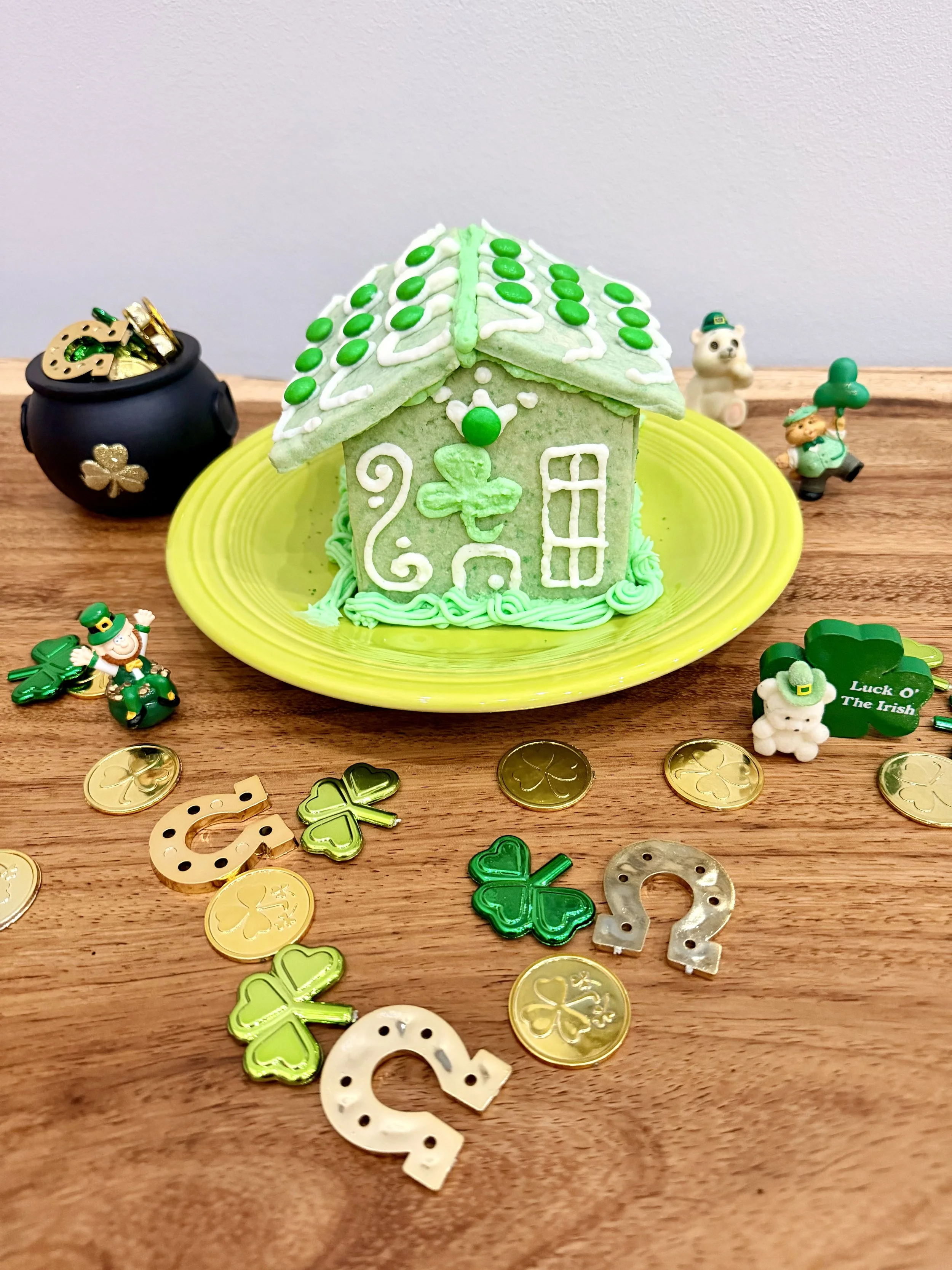 Back view of a decorated leprechaun trap sugar cookie house with shamrock icing details and green buttercream for St. Patrick’s Day.