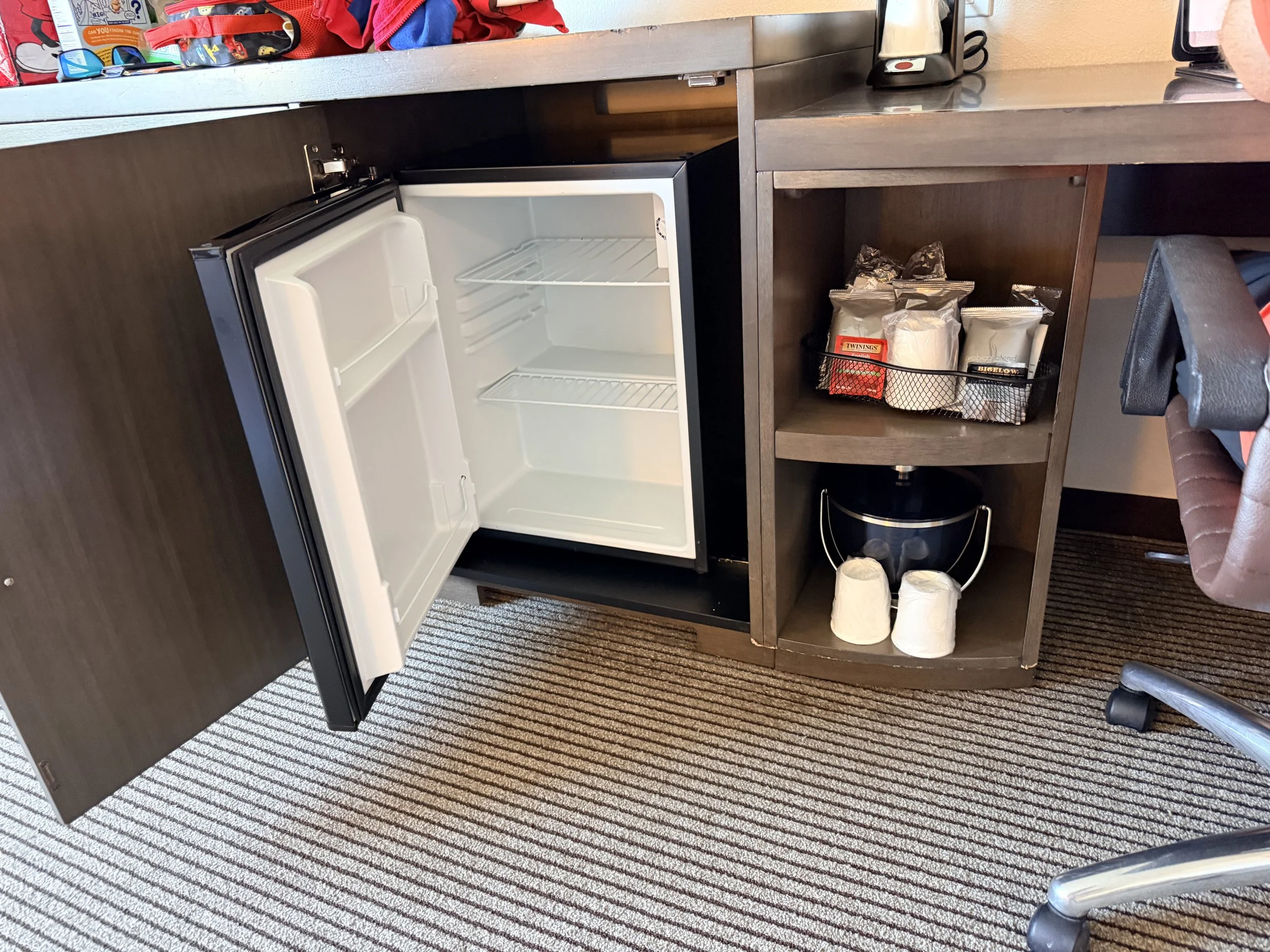 Hyatt Place Santa Cruz Hotel room with open mini fridge that is empty and a coffee maker and coffee options.