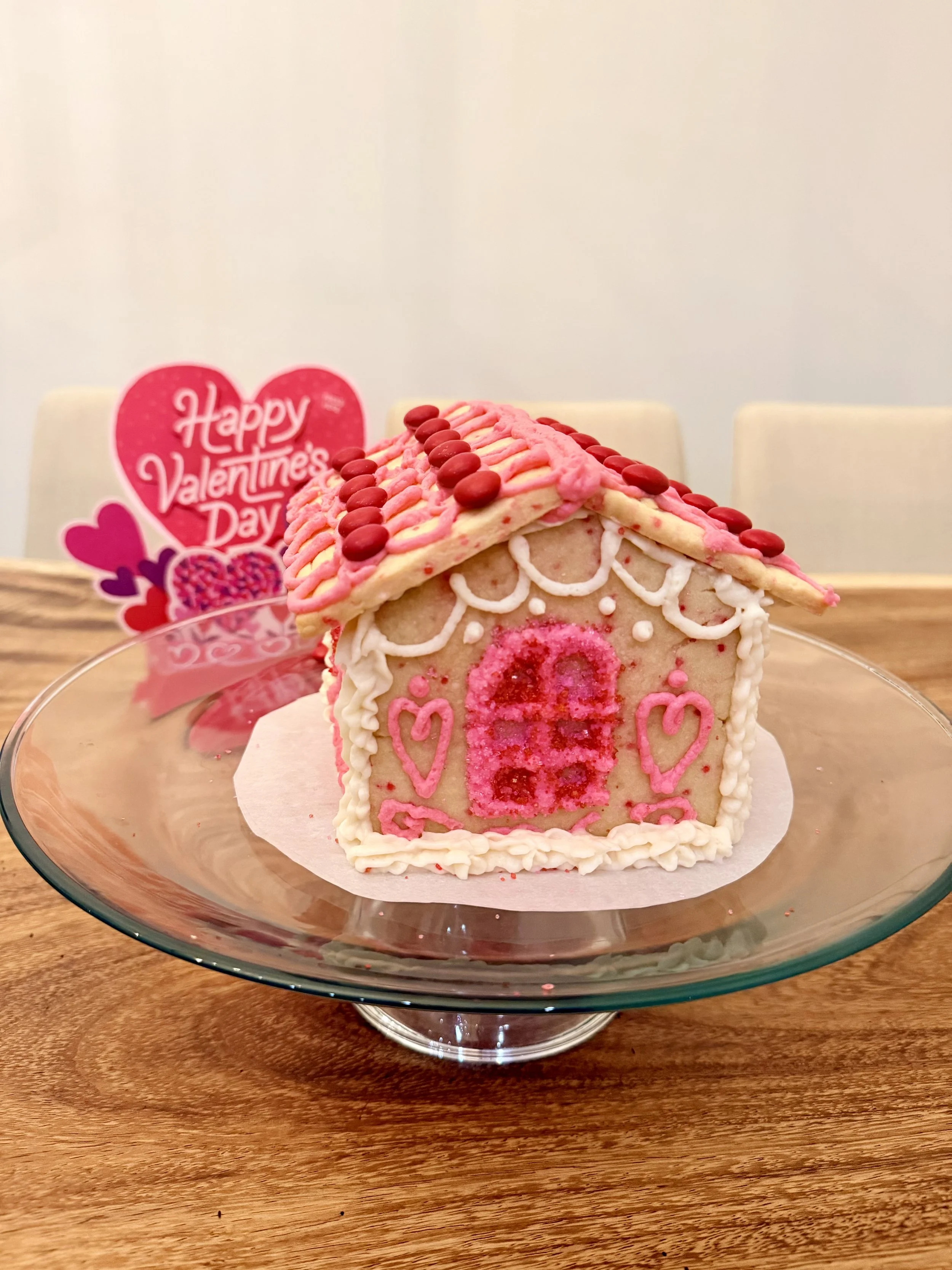 Valentine’s Day sugar cookie house decorated with pink buttercream and heart candies